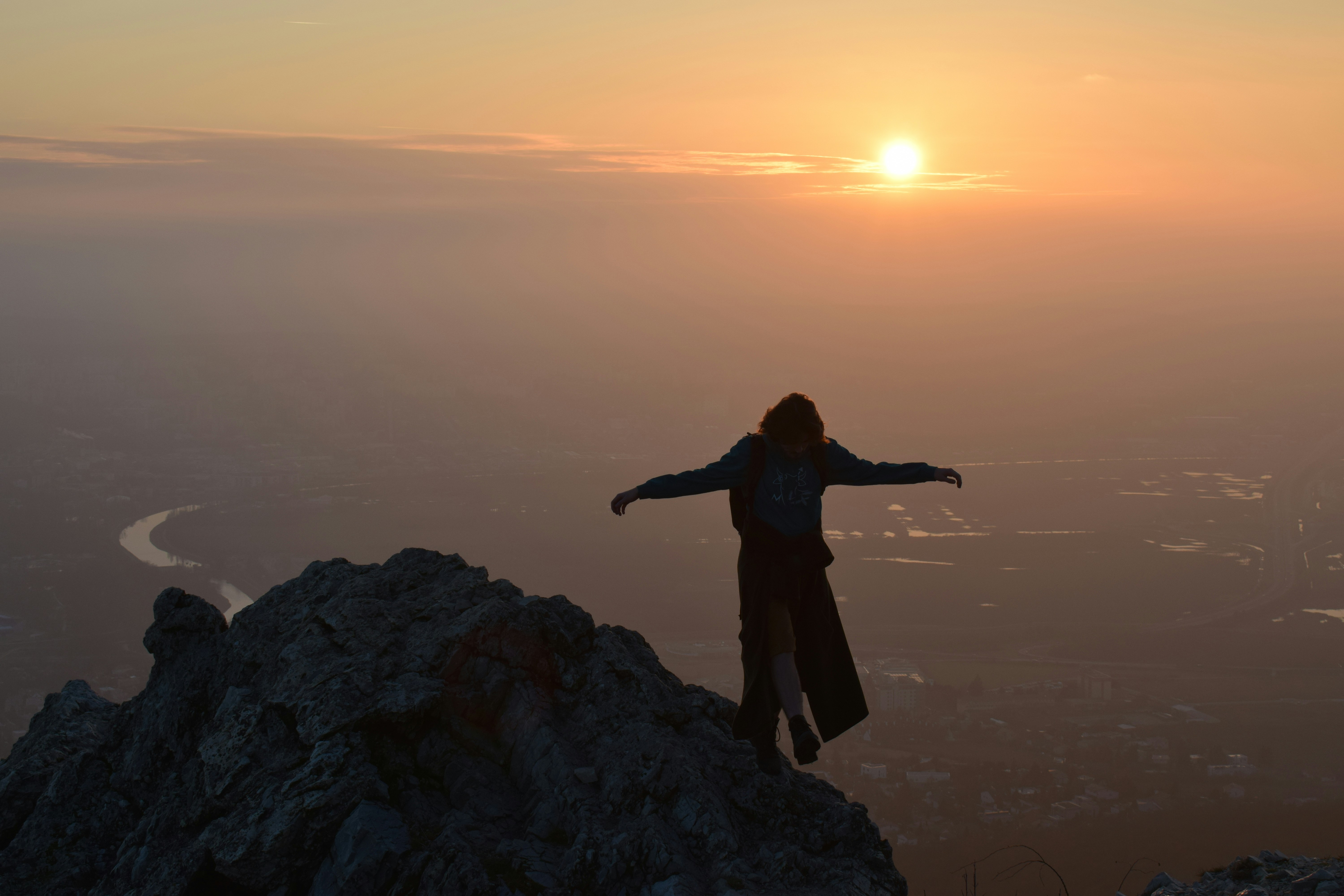 Person standing on mountain peak at sunset