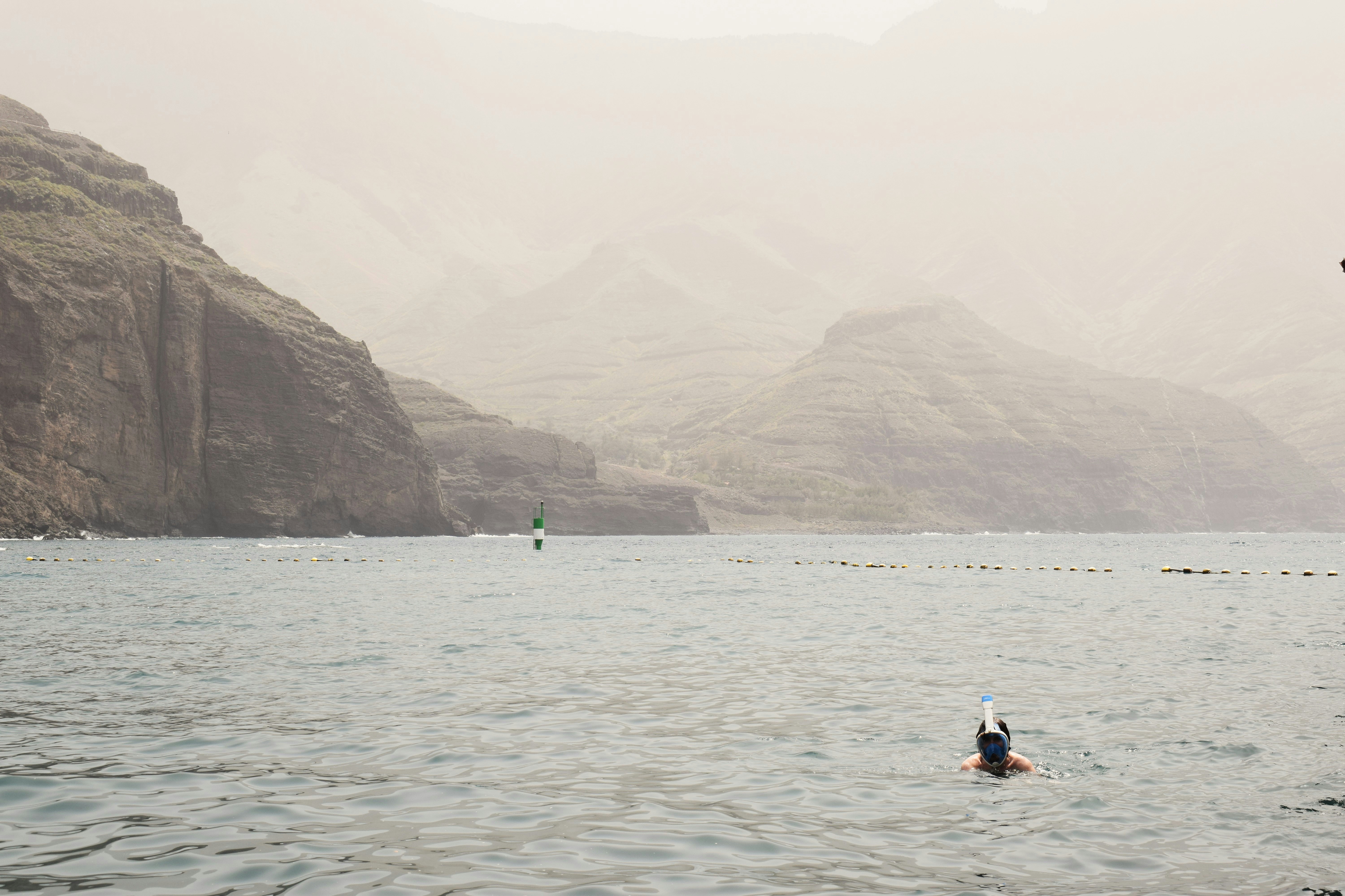 Man snorkeling in the ocean near rocky cliffs