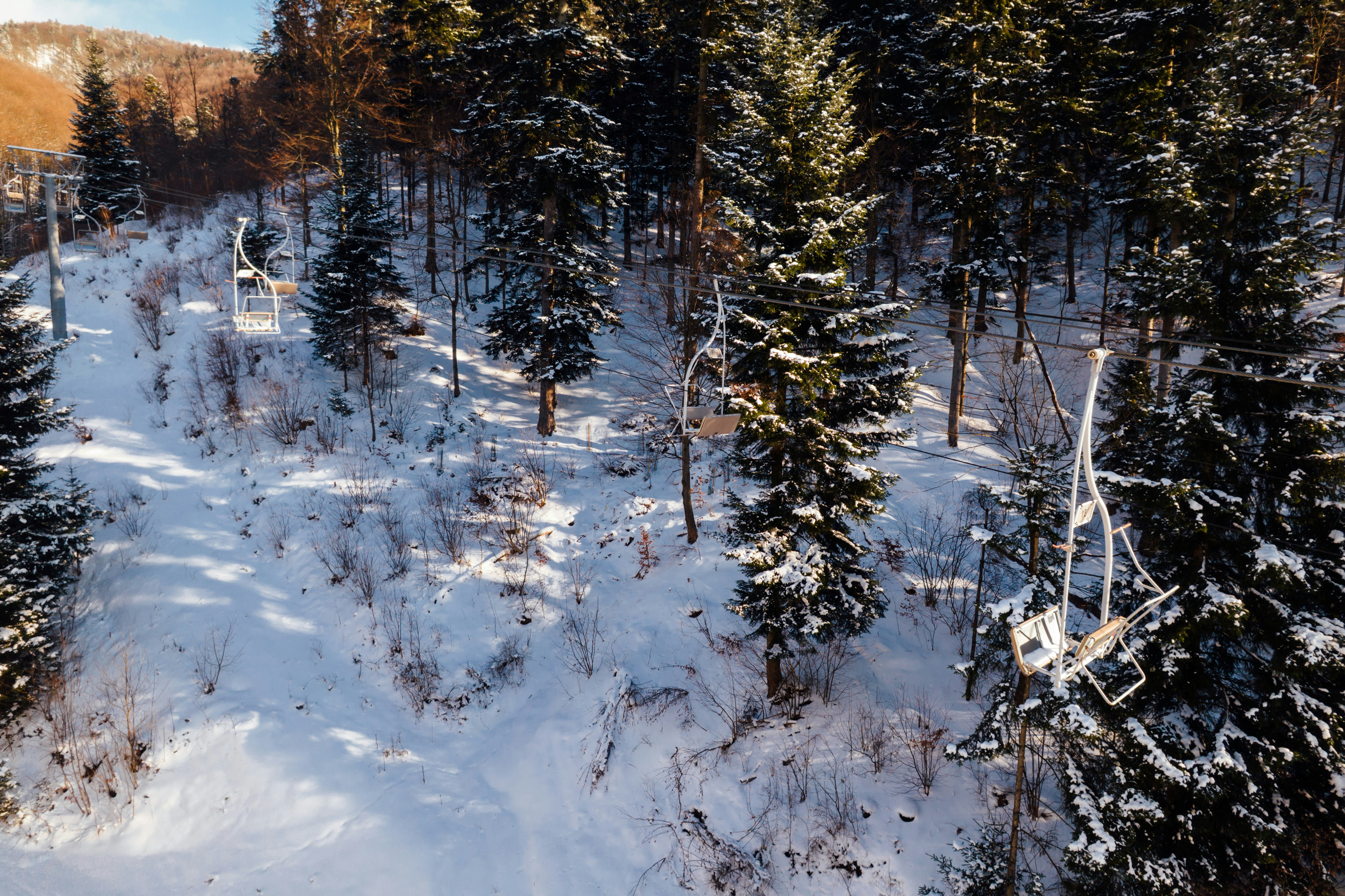 Ski lift chairs ascend a snow-covered mountain slope.