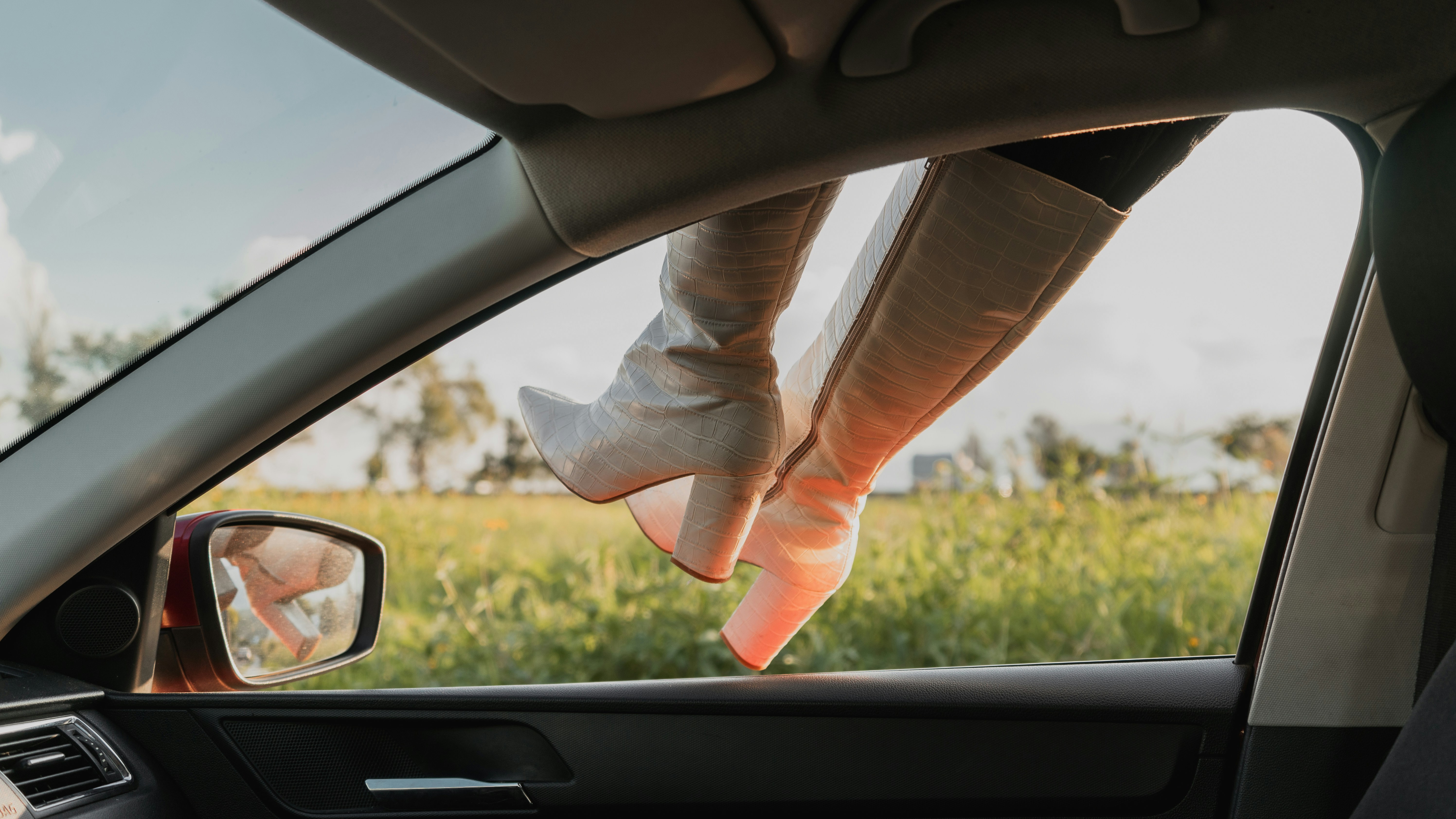 Woman's legs in white boots hang out car window