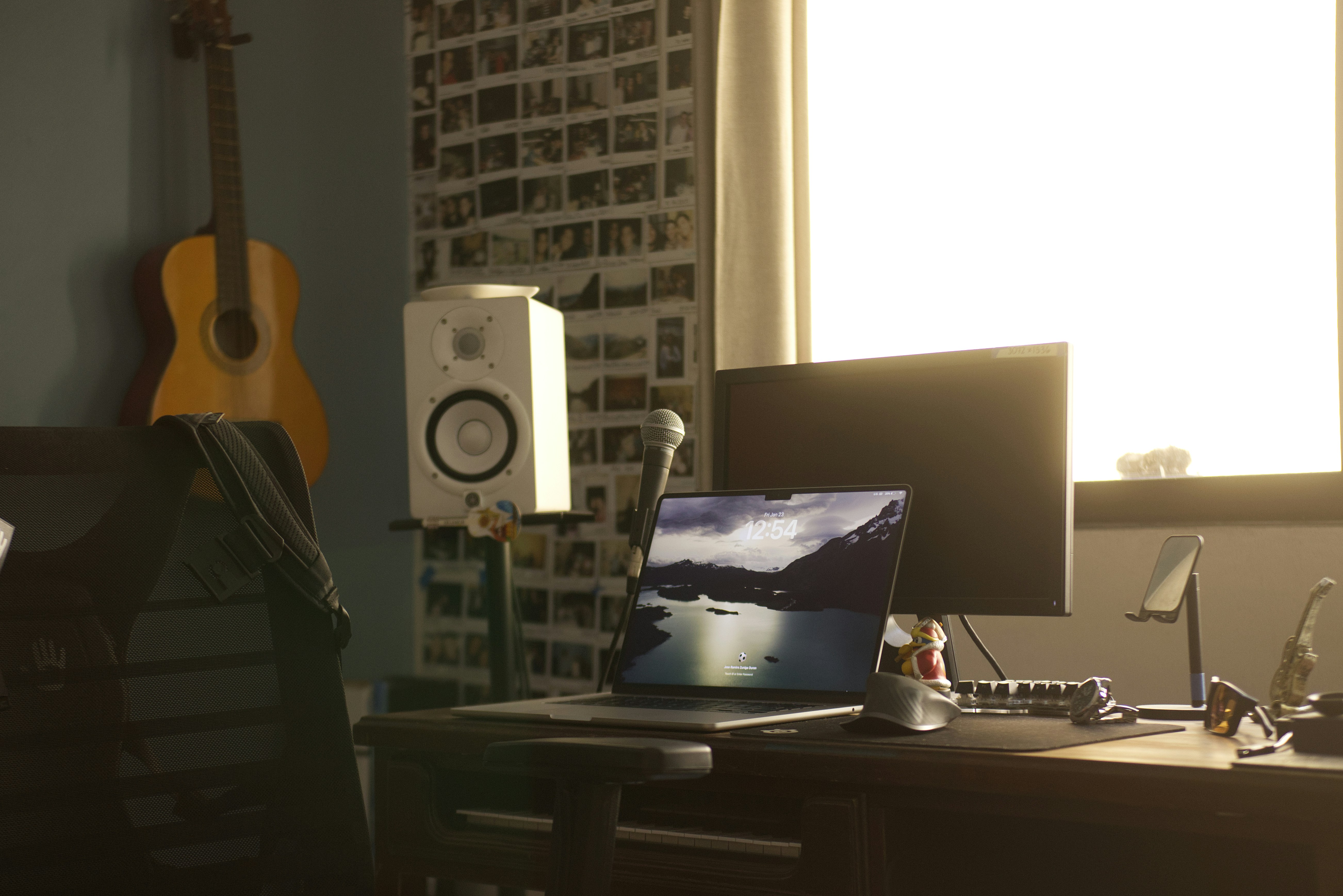 Desk with laptop, monitor, and guitar