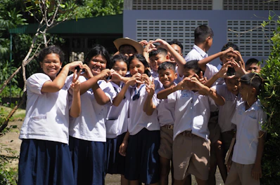 Children in uniform make heart shapes with hands