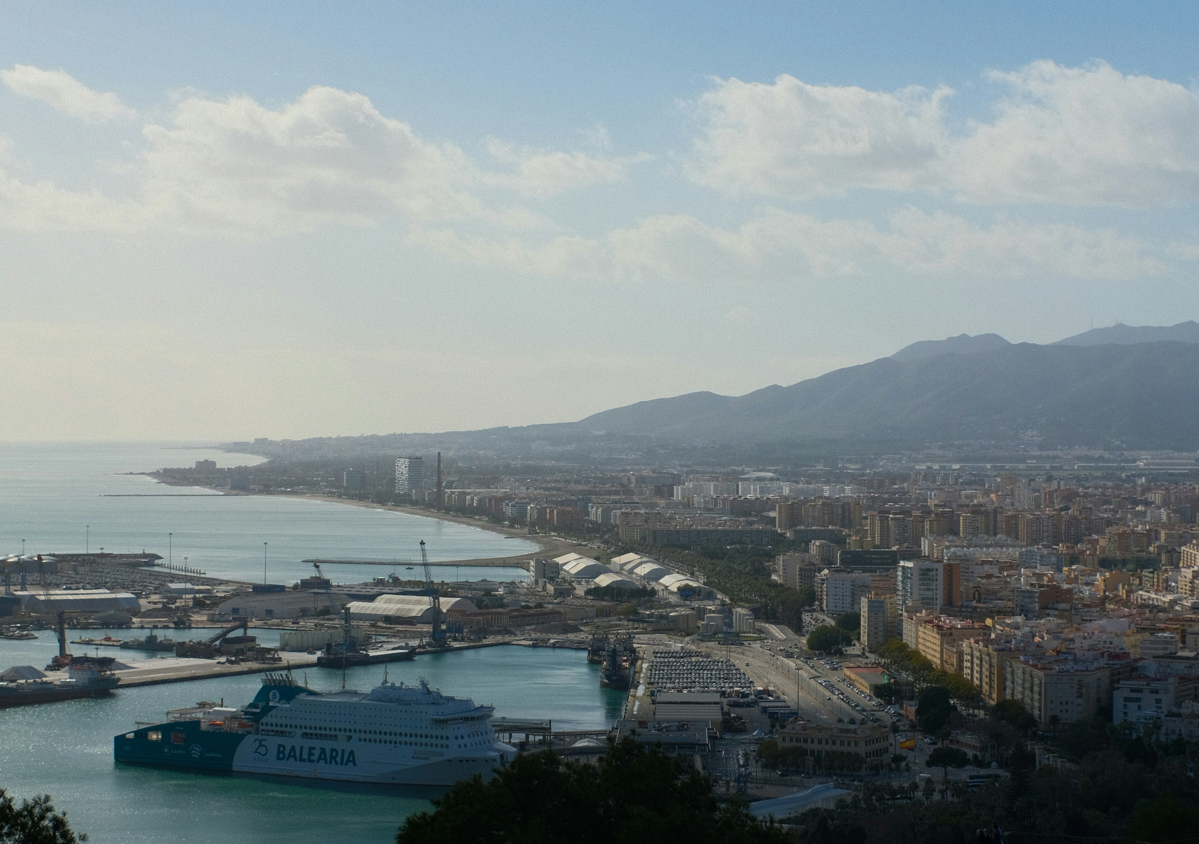 Küstenstadt mit einem belebten Hafen und fernen Bergen.