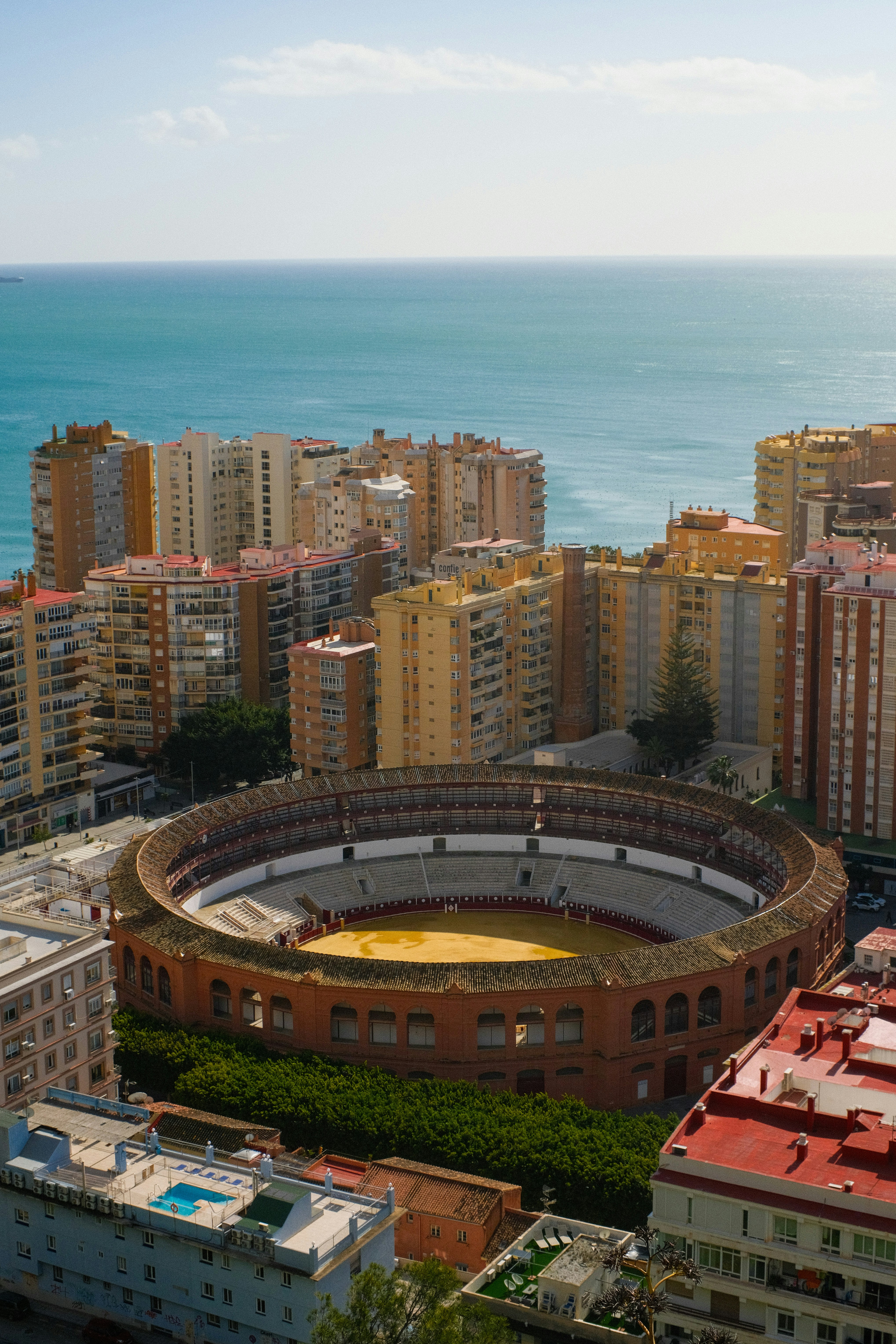 Stierkampfarena umgeben von Gebäuden, hinter dem Ozean.