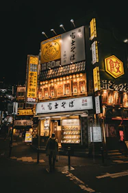 A lone person walks down a street at night.