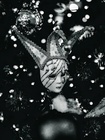 A jester mask hangs on a christmas tree