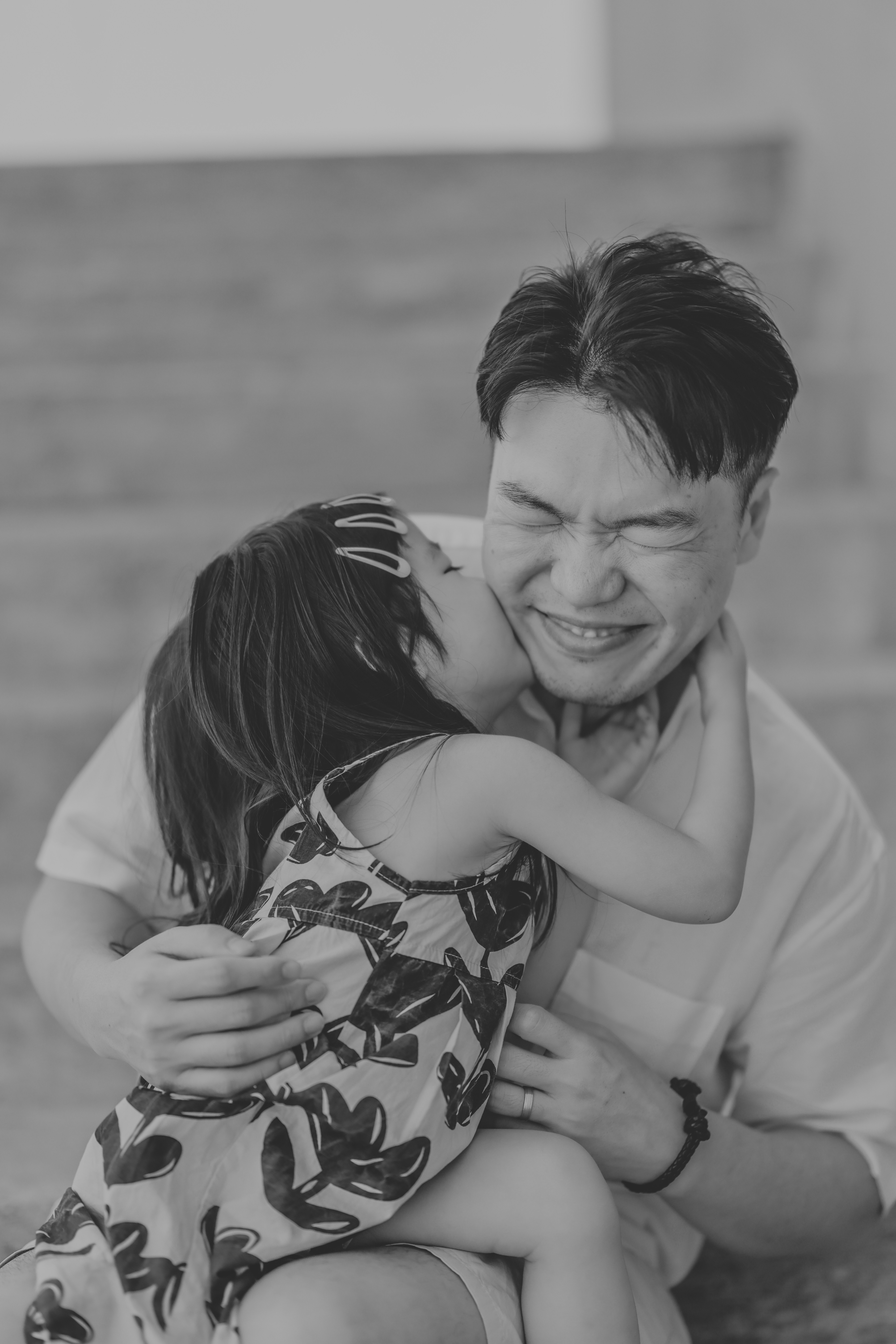 A girl kisses her father on the cheek.