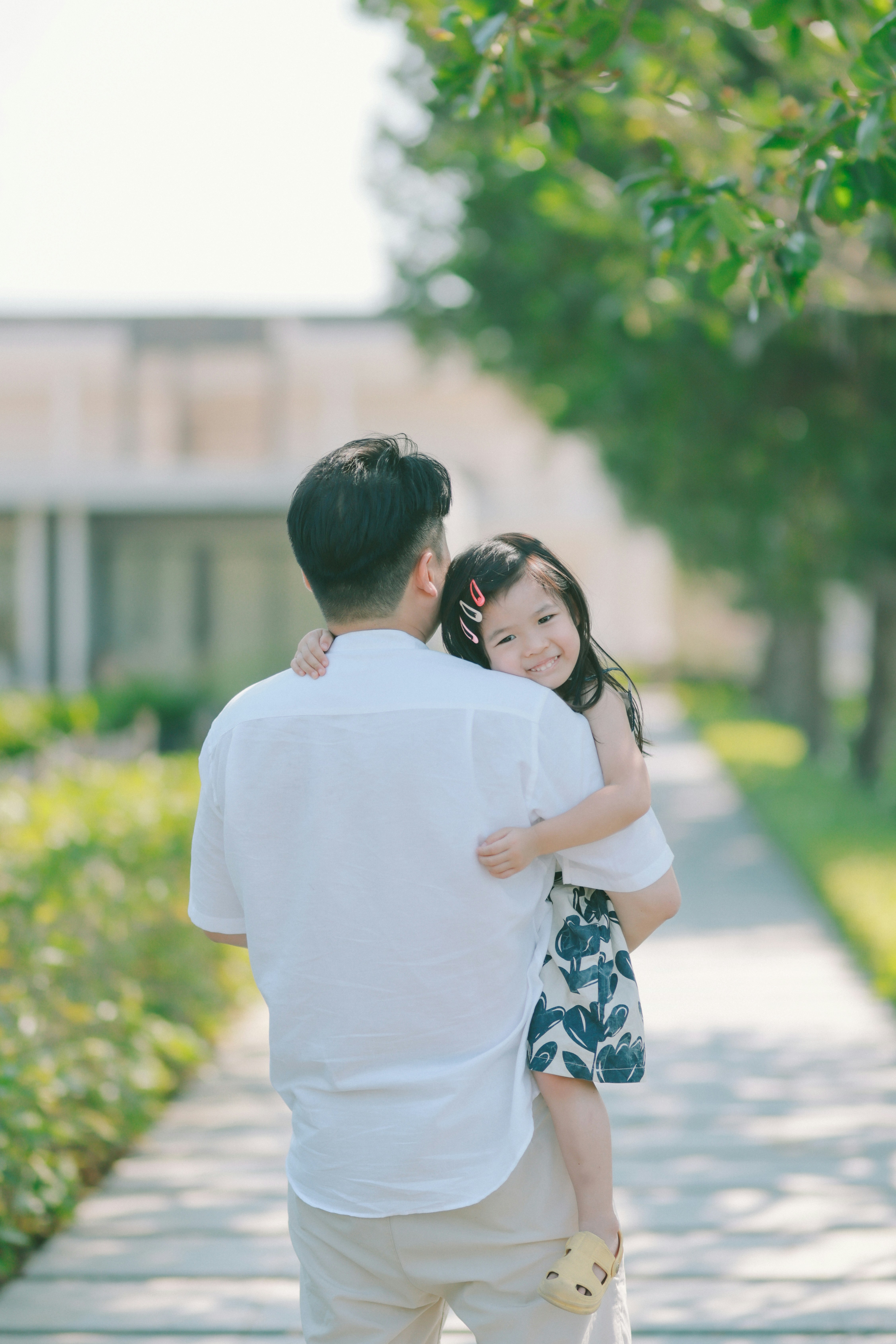 Father holding his smiling daughter in a park.