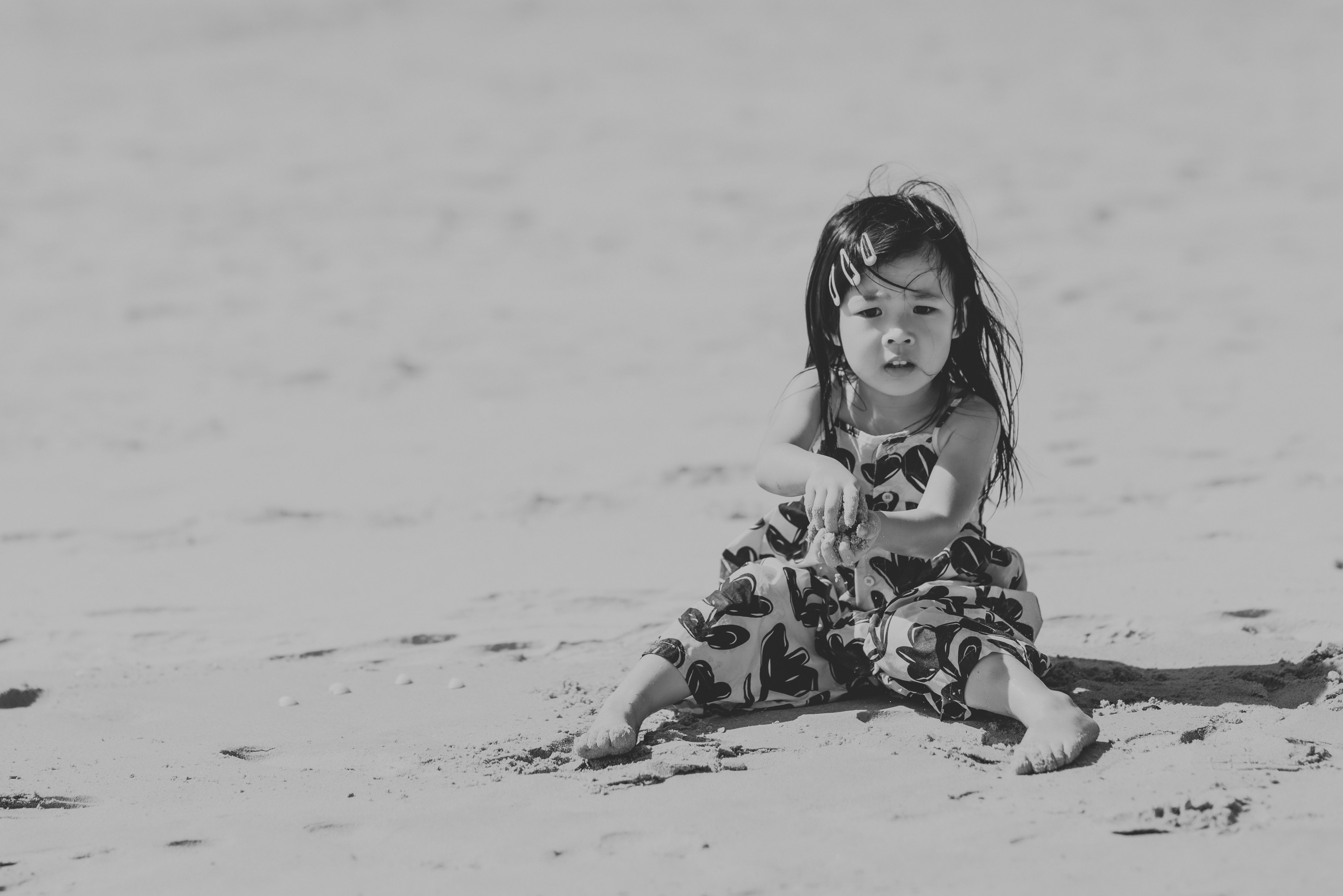 Young girl sitting on a sandy beach in monochrome