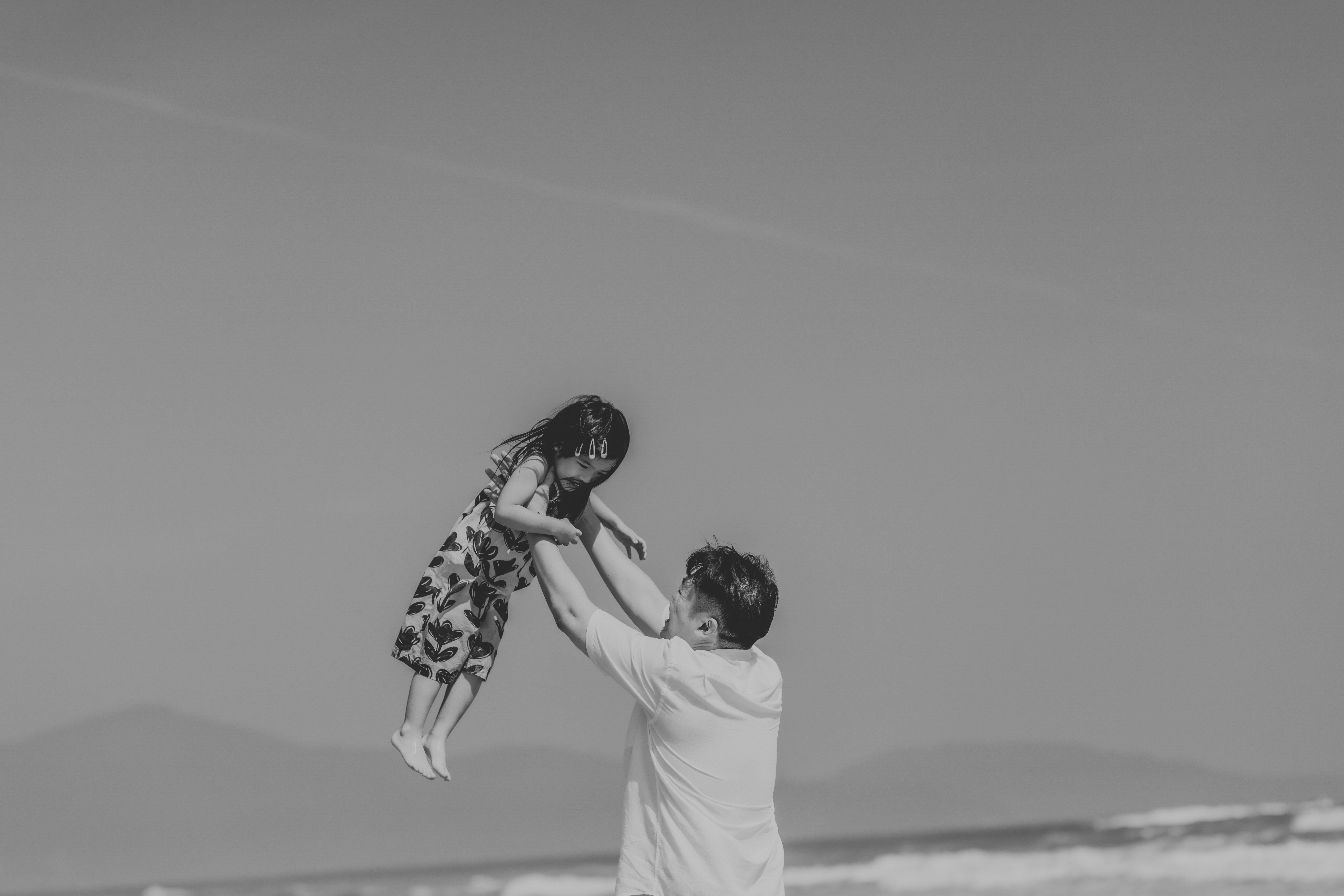 Father throwing daughter in the air at the beach