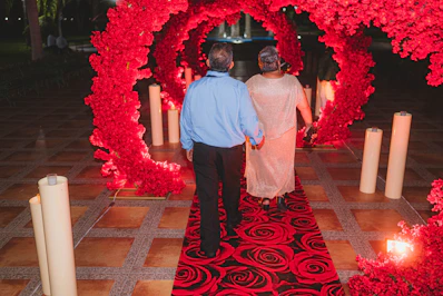 Couple walks through a red floral heart archway