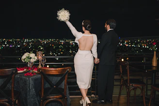 Couple on a balcony overlooking a city at night