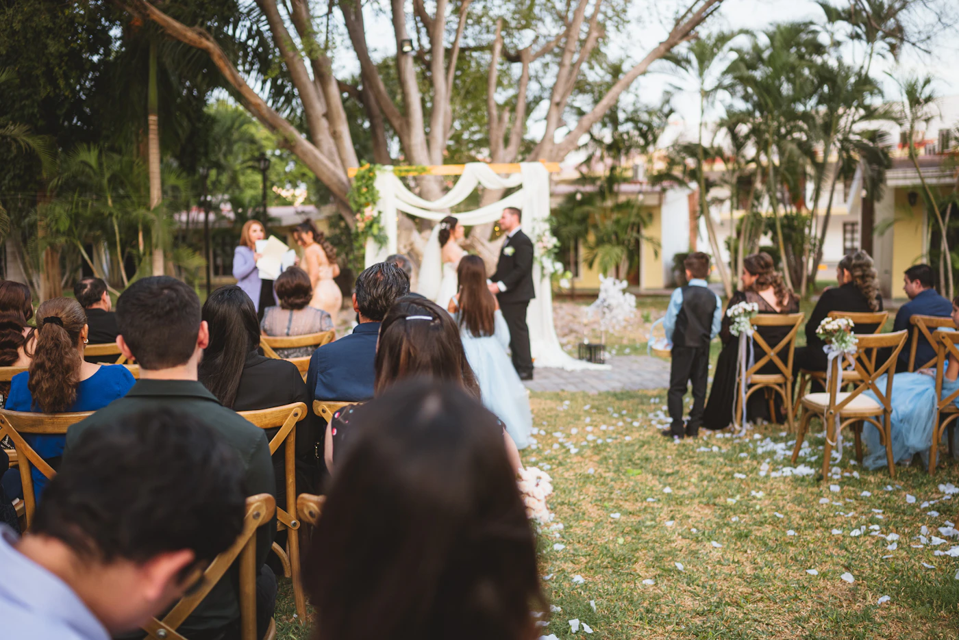 Couple in wedding attire exchanging vows surrounded by lush garden blooms
