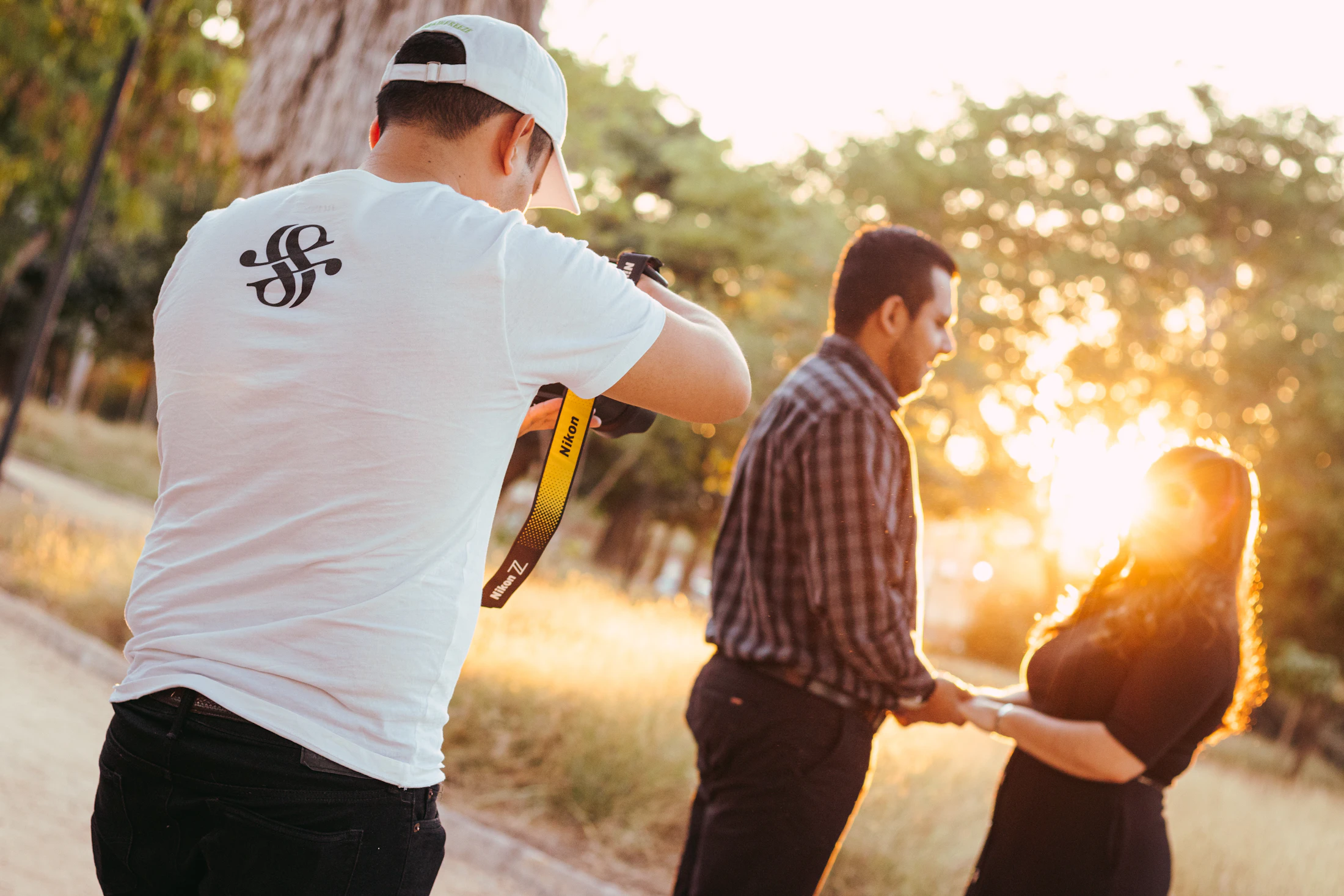 Photographer photographing a couple outdoors at golden hour.