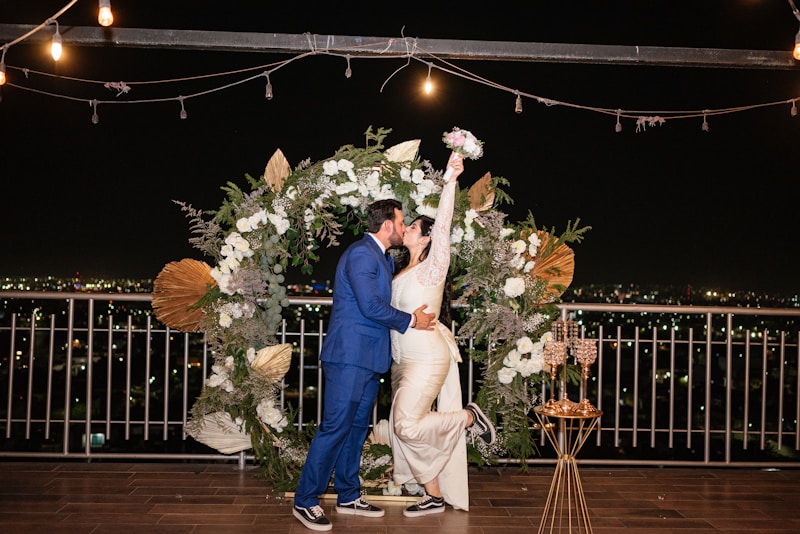 Novia y novio besándose bajo arco floral