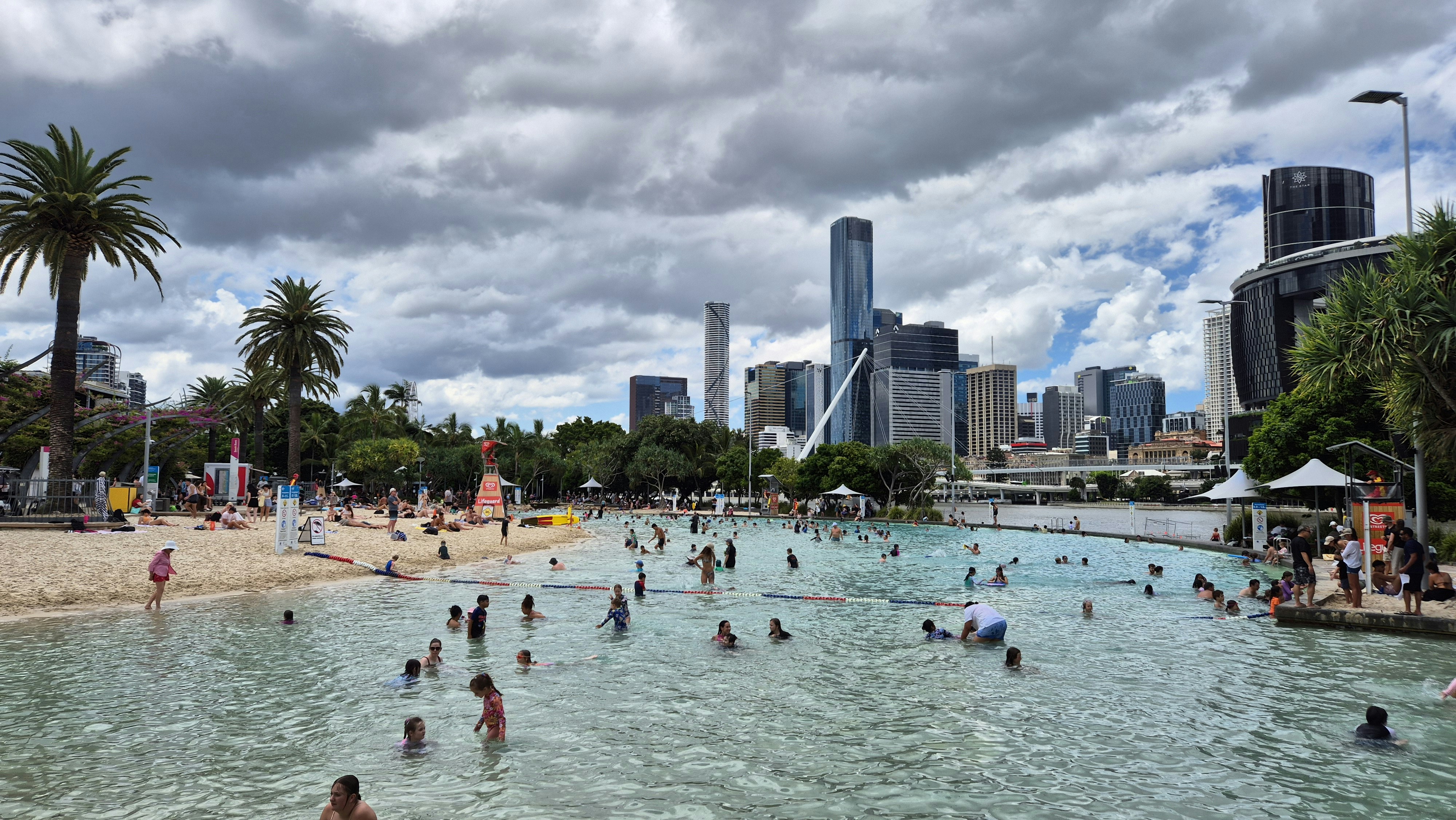 Le persone nuotano in una laguna con lo sfondo dello skyline cittadino.