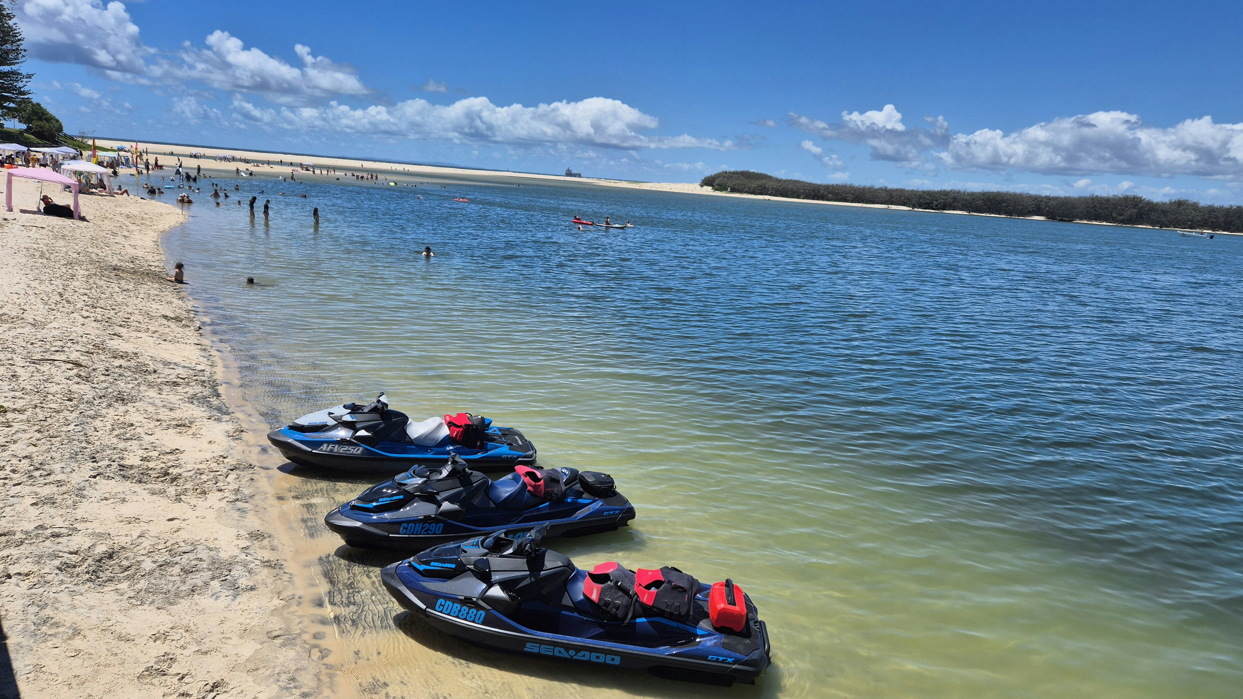 Tre moto d'acqua parcheggiate su una spiaggia sabbiosa vicino all'acqua.