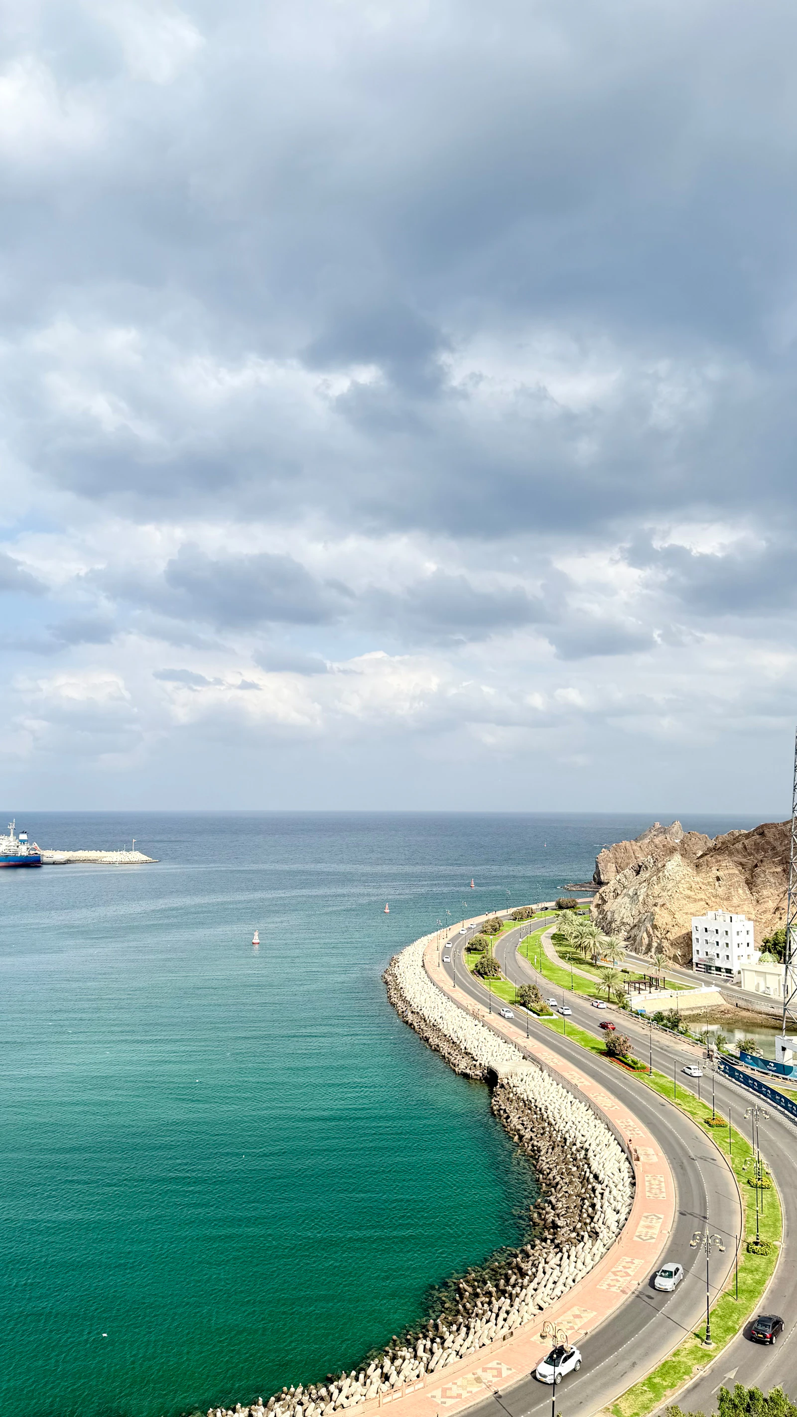 A coastal road curving above turquoise water in Oman