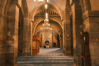 Interior of a grand mosque with arched ceilings and chandelier
