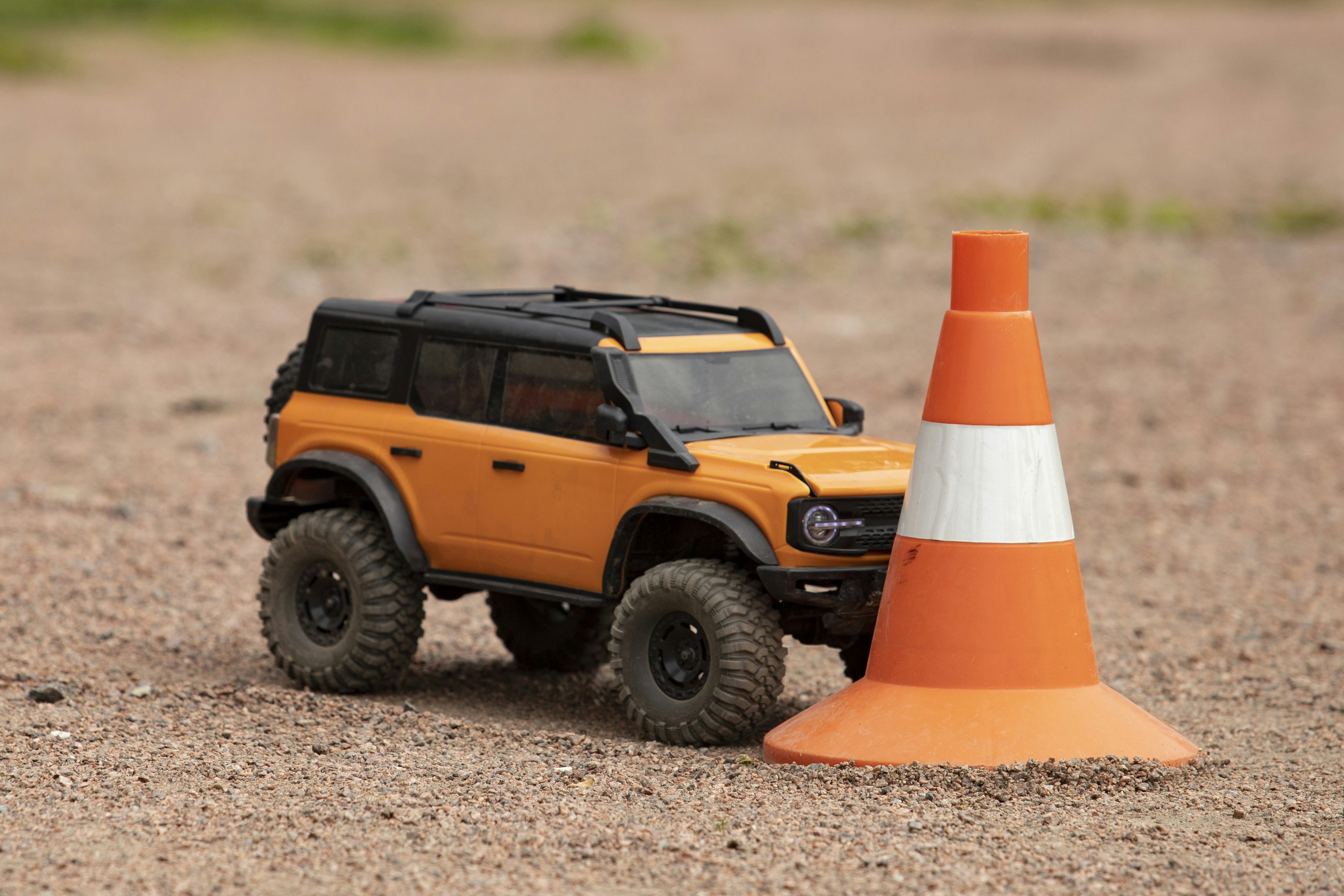 Orange toy suv next to traffic cone