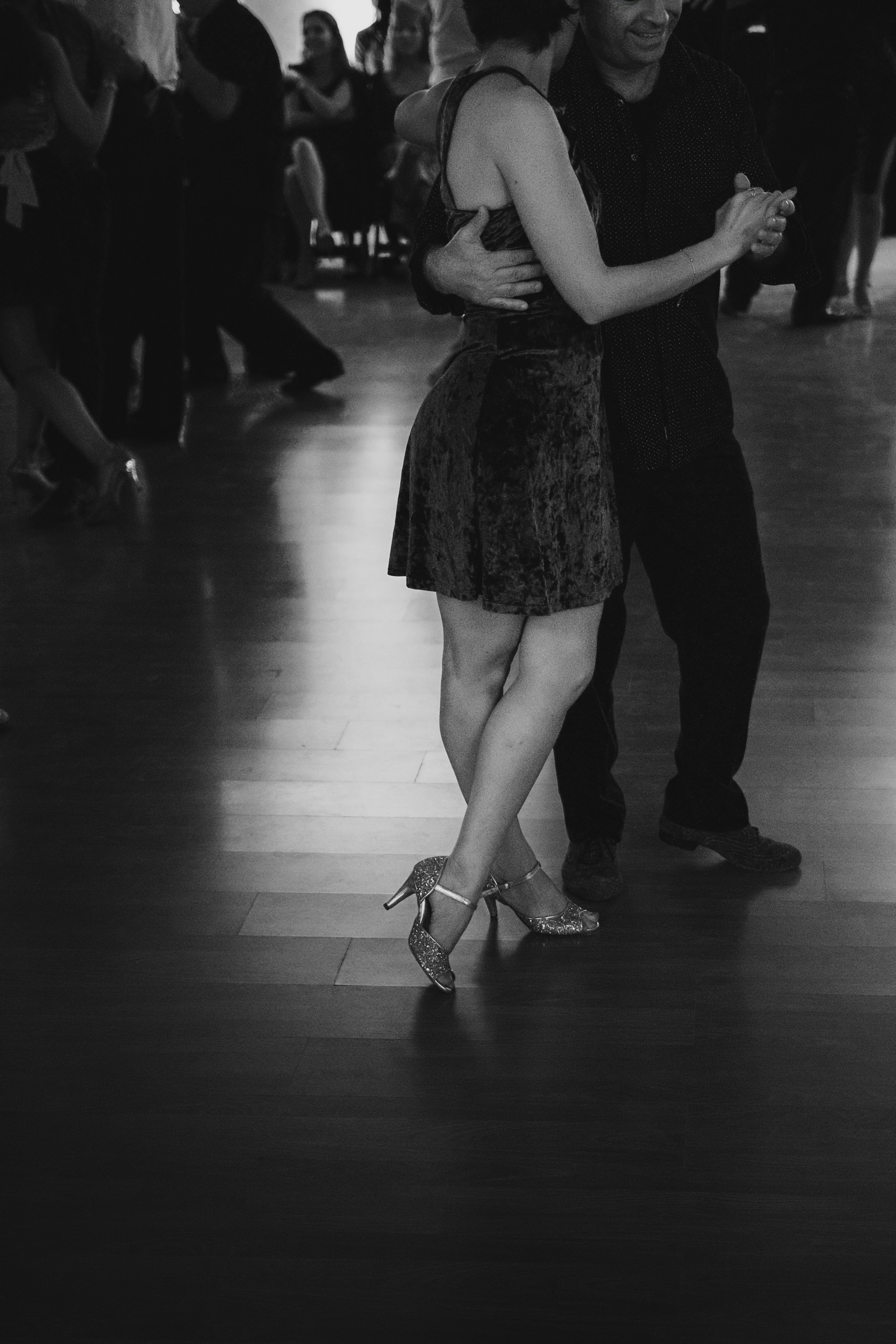 Couple dancing tango on a polished wooden floor.