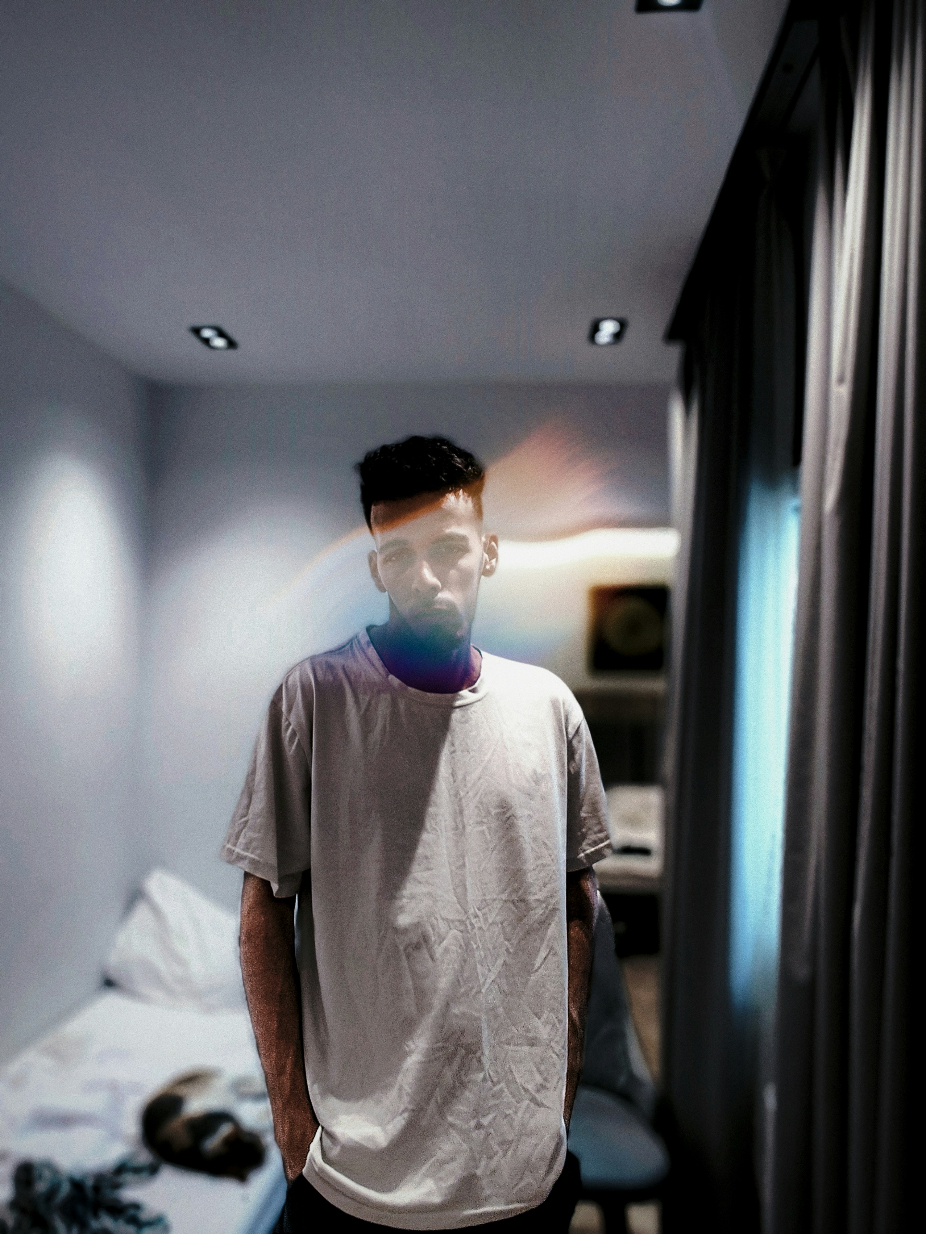 A man in a t-shirt stands in a room.