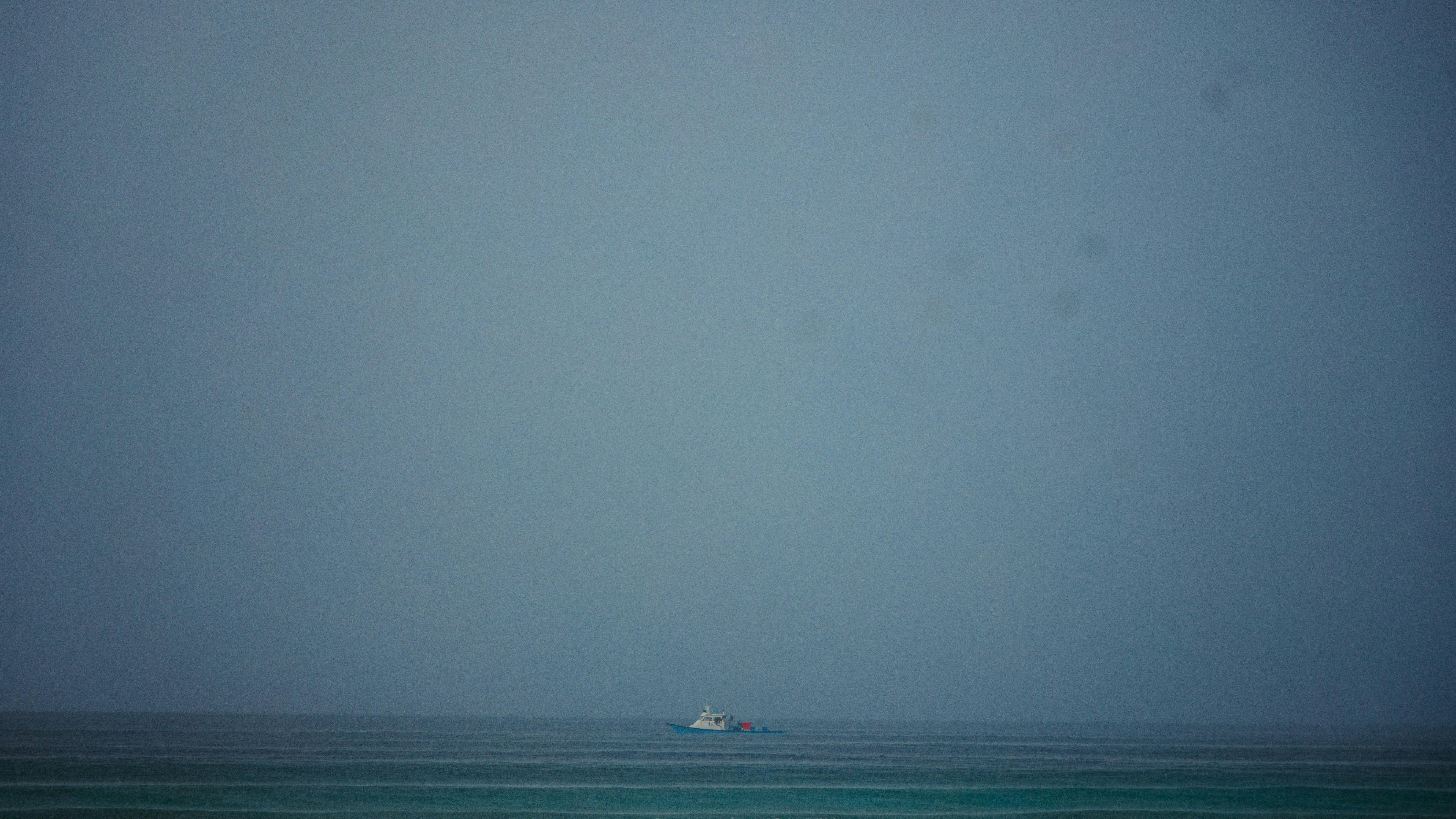A small boat sails on a choppy, grey ocean.