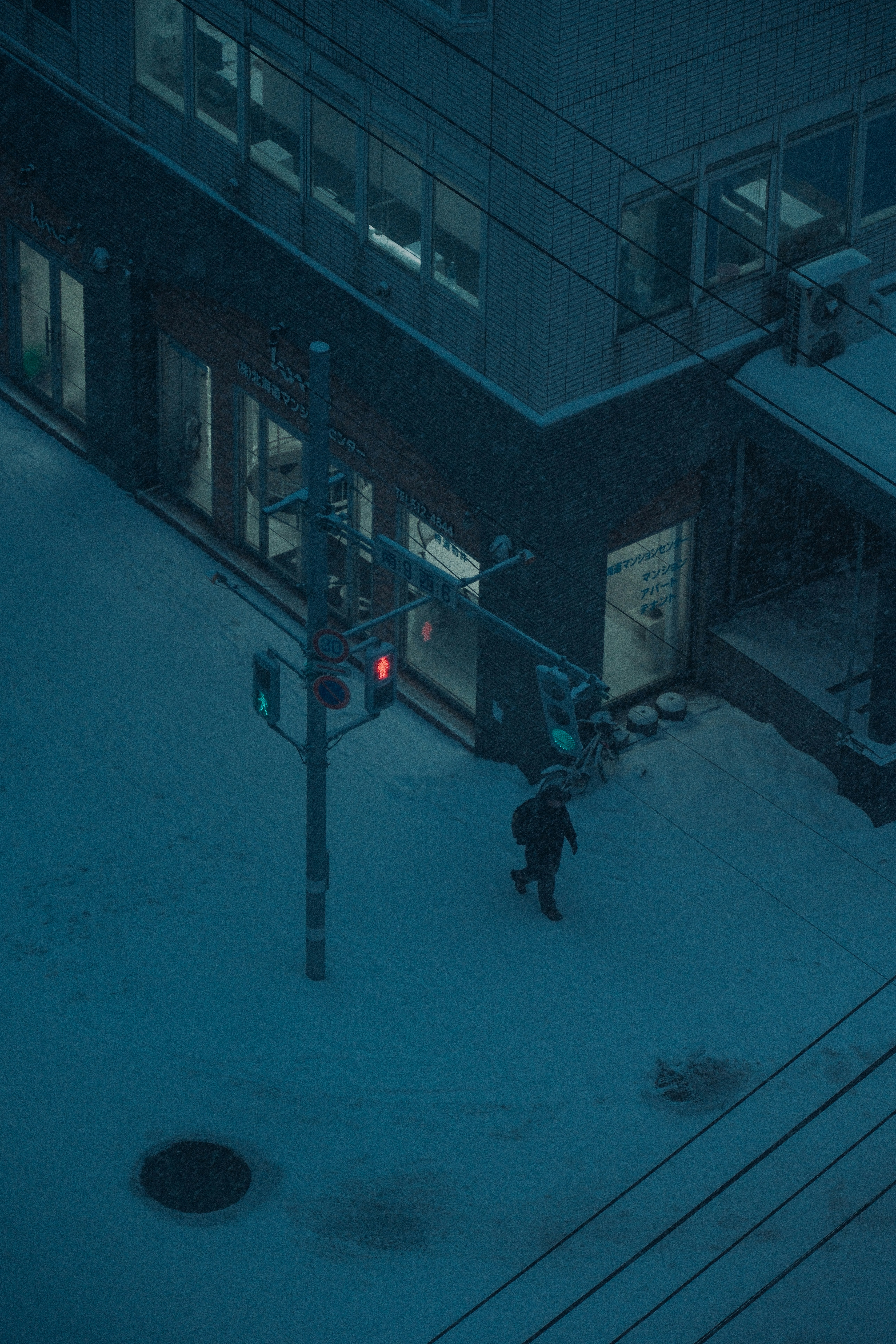 A person walks on a snowy street at night.