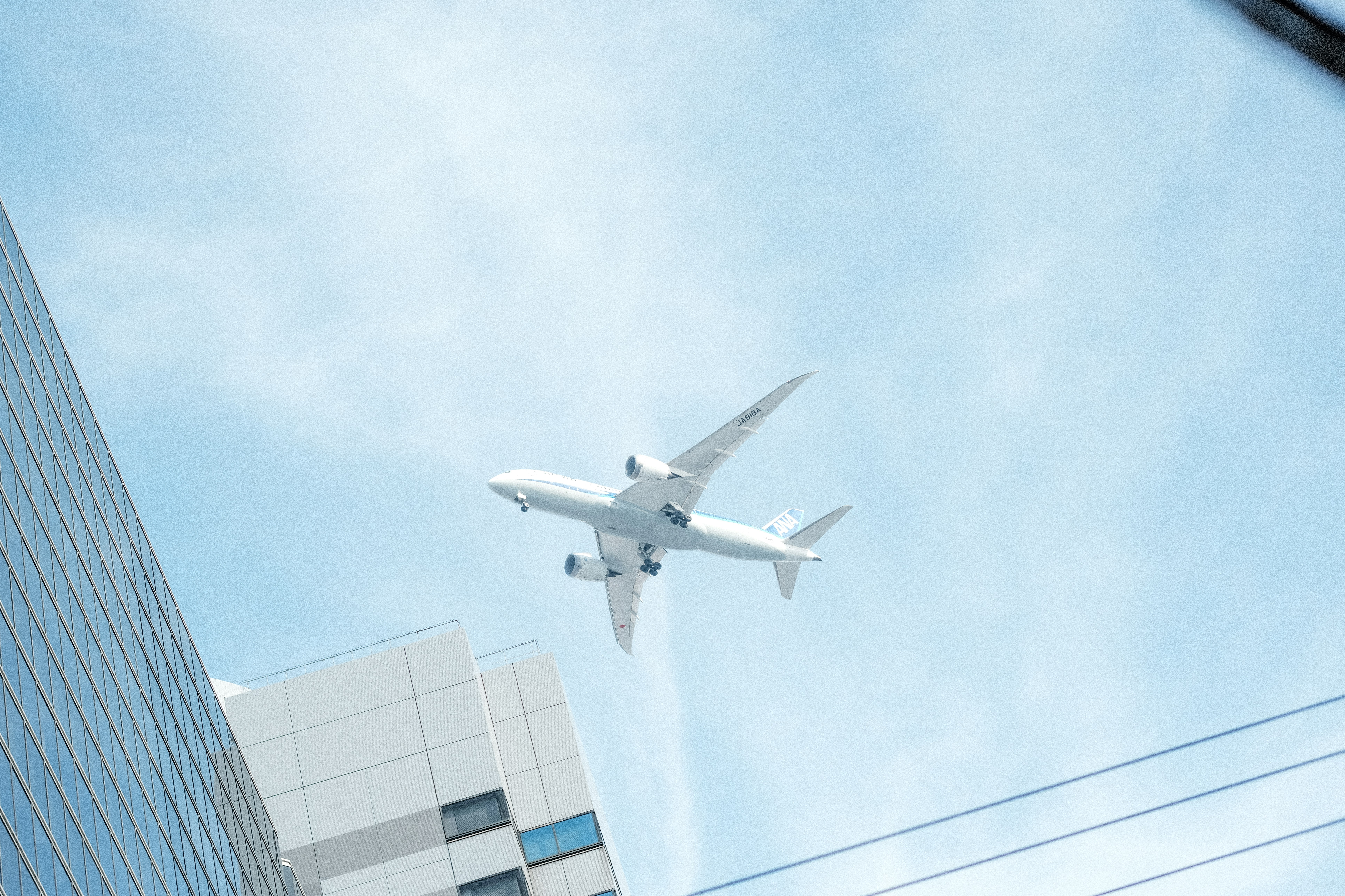 Ein weißes Flugzeug fliegt über Gebäuden am Himmel.