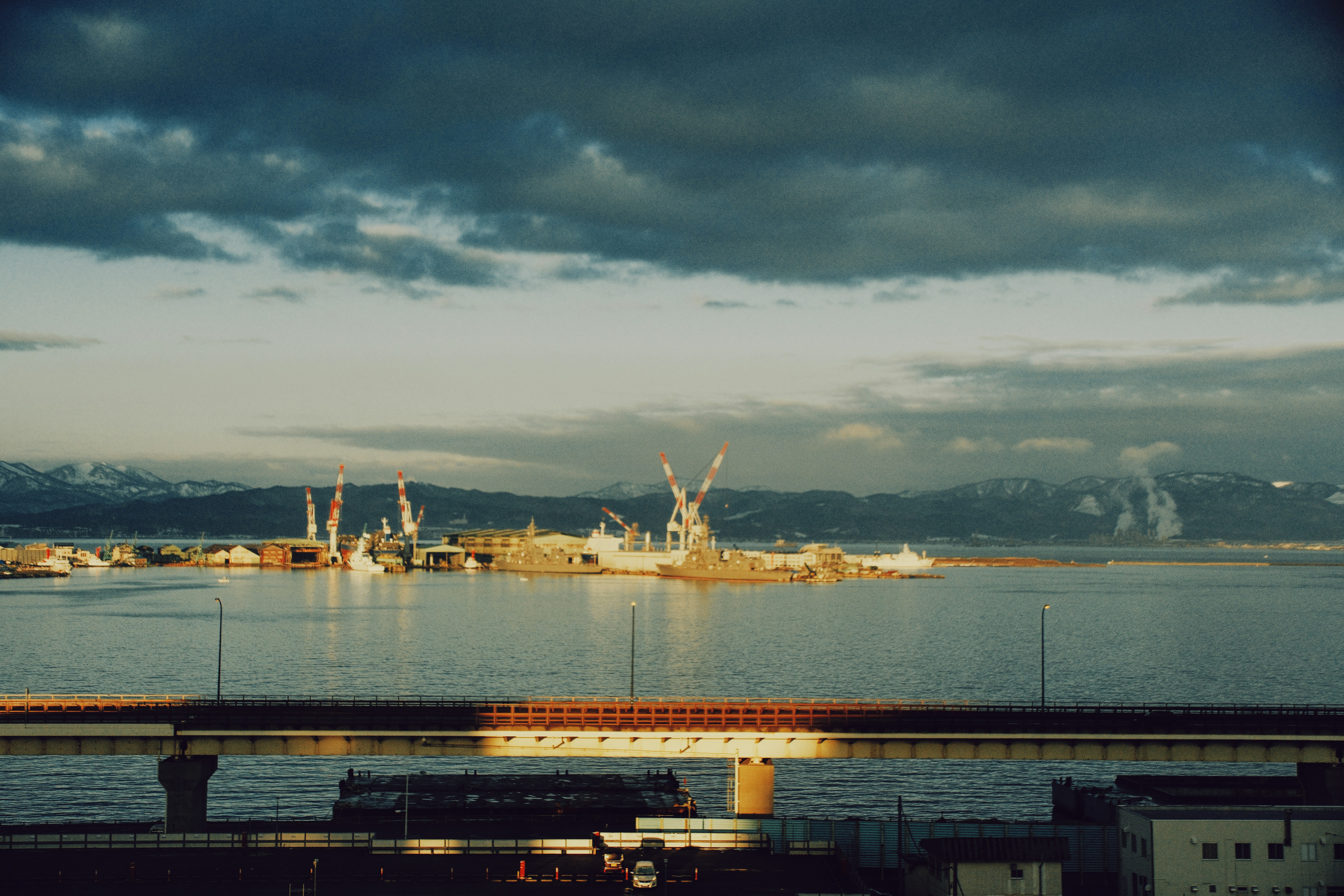 Industrial port with cranes on the water at dusk.