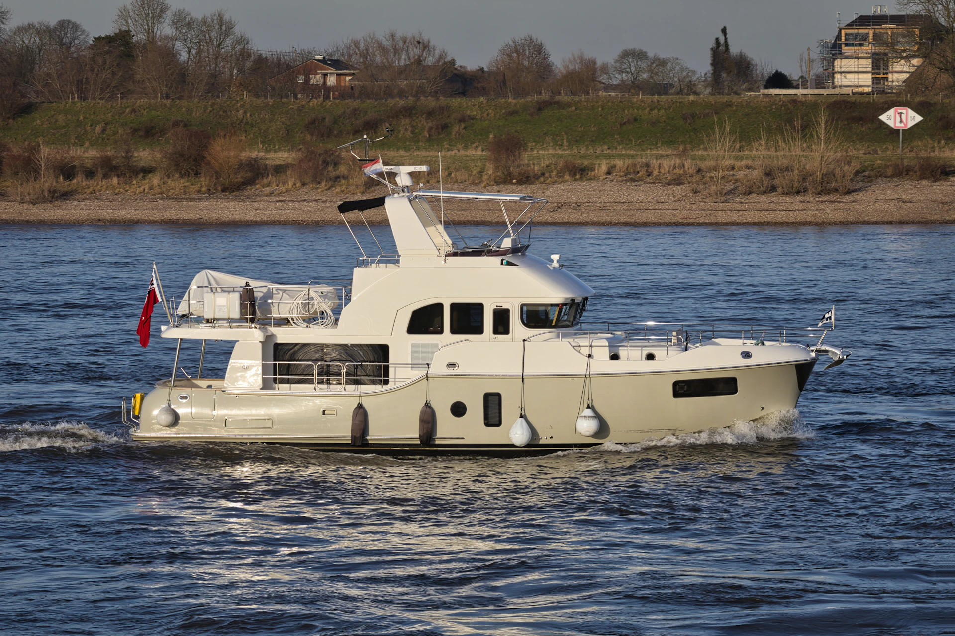 A white and grey motor yacht sailing on a river