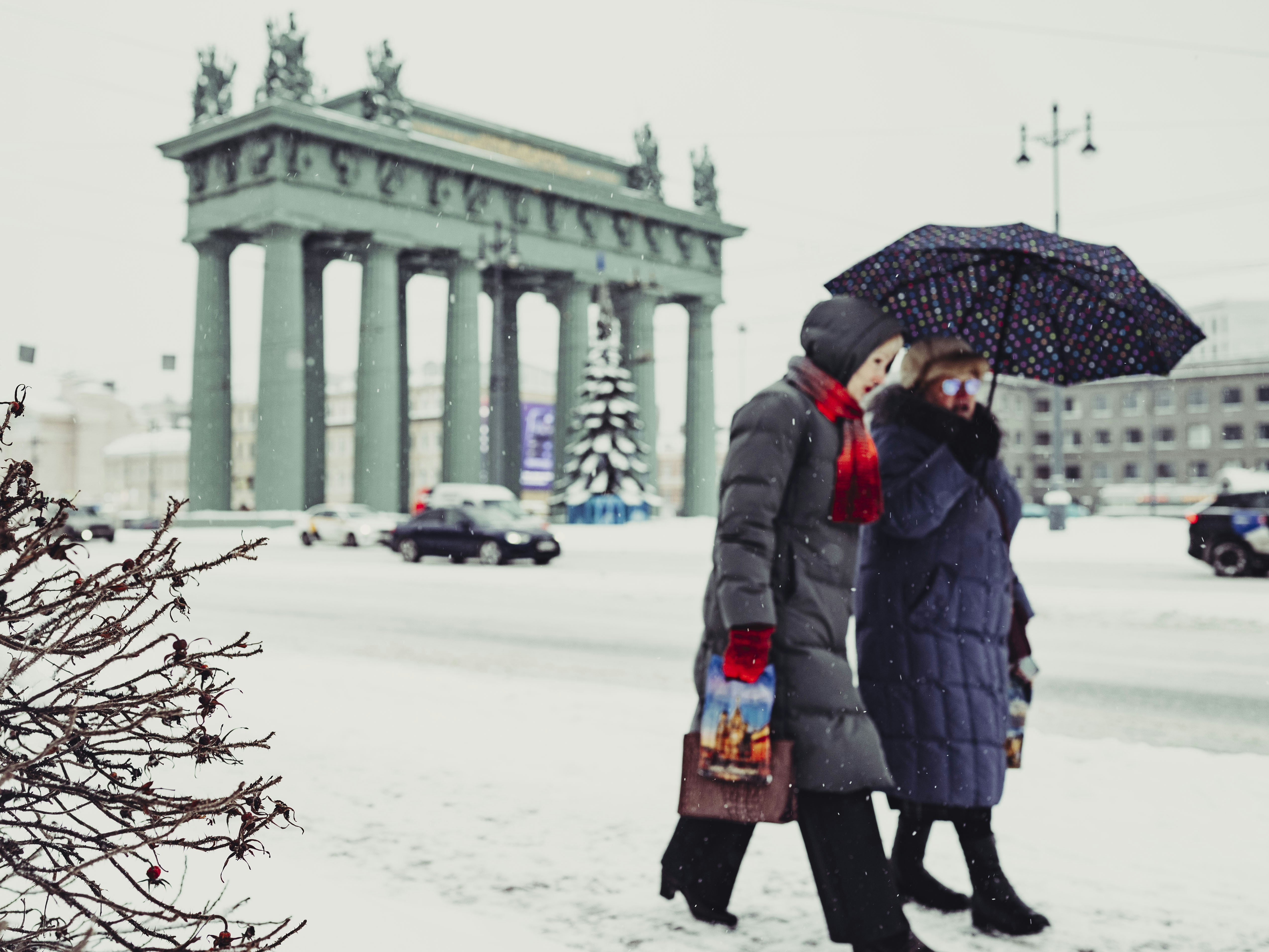 Two people walk under an umbrella in snowy weather.