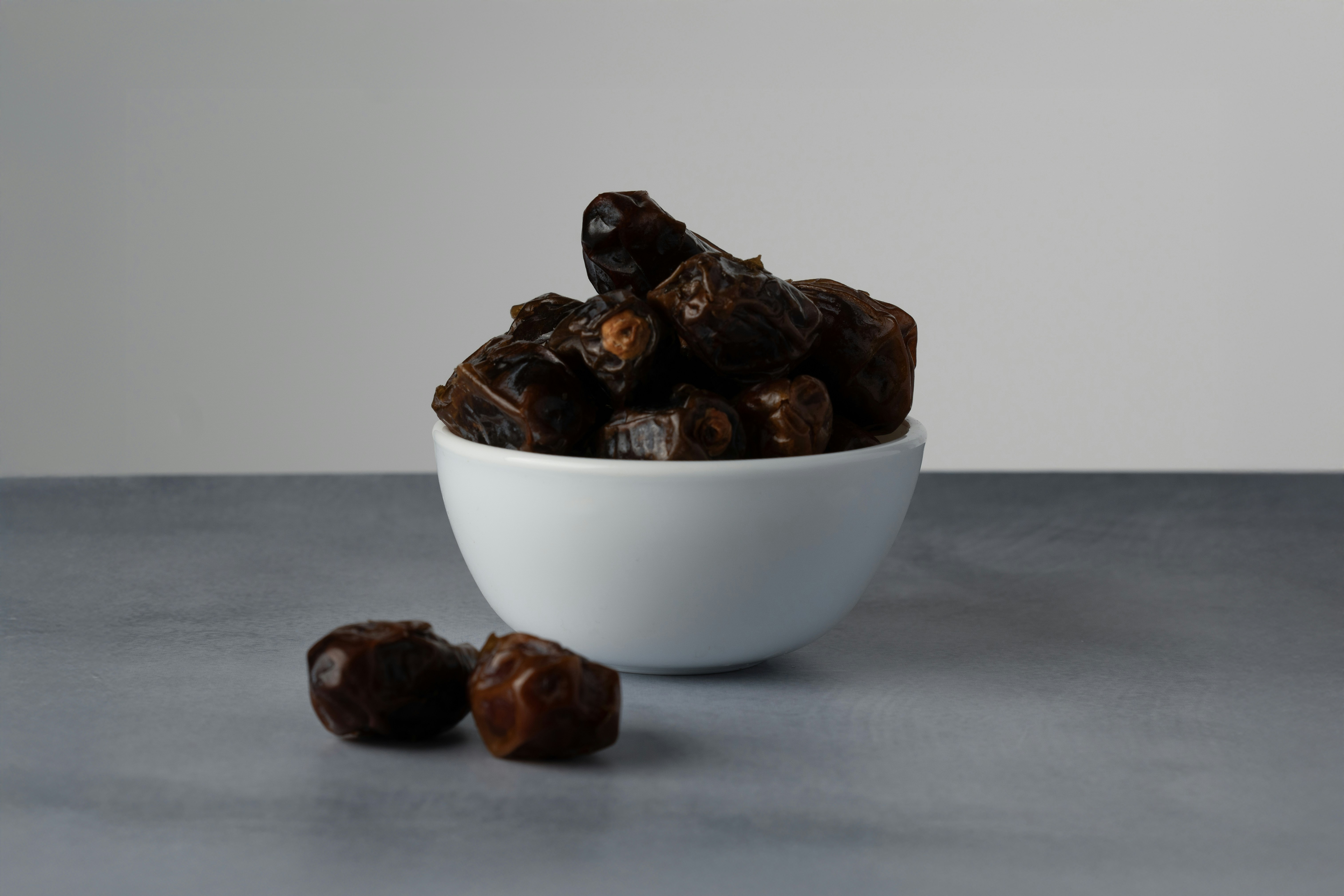 A bowl of dates with two dates in front