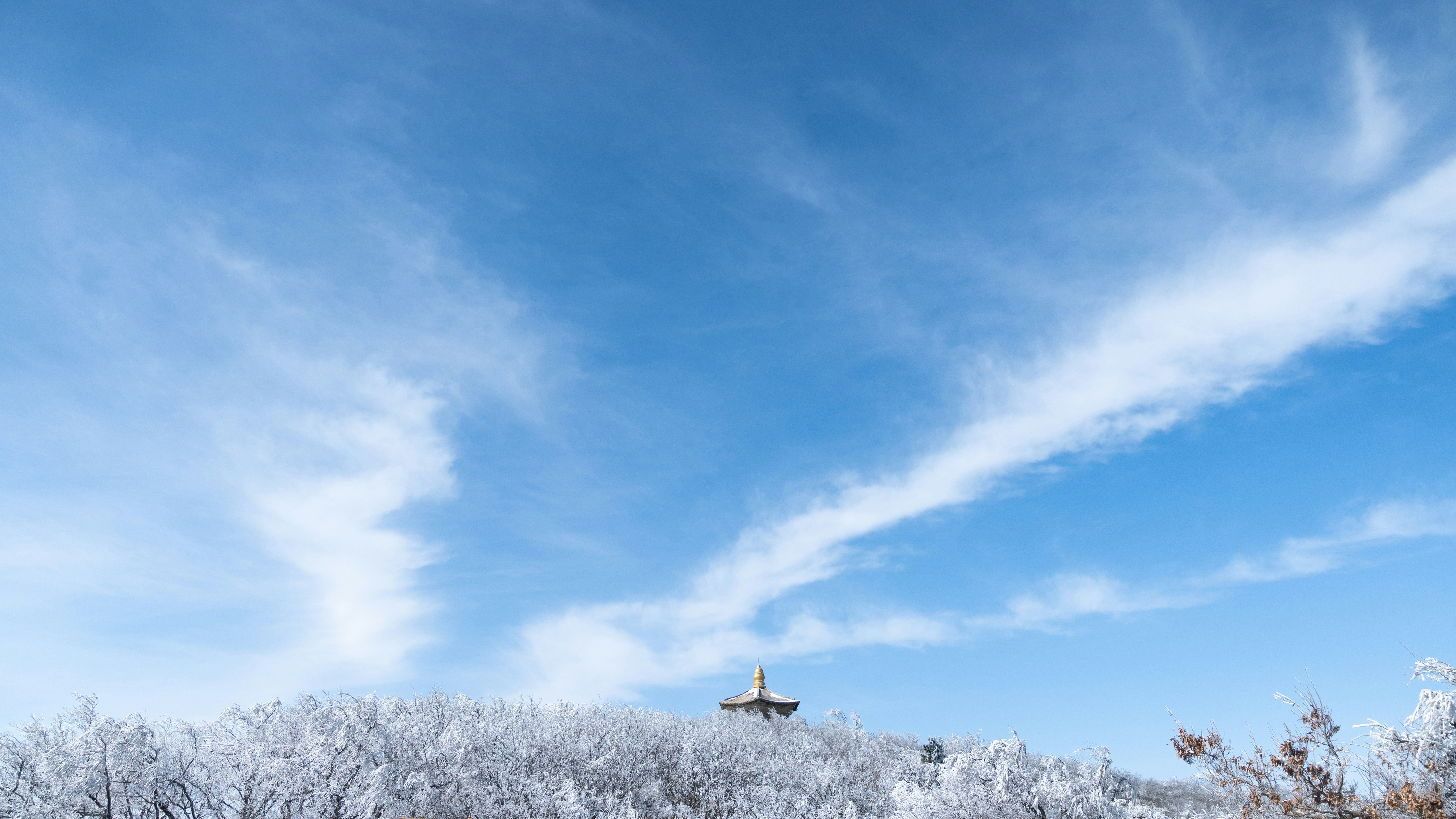 A tower atop a snow-covered hill under a cloudy sky