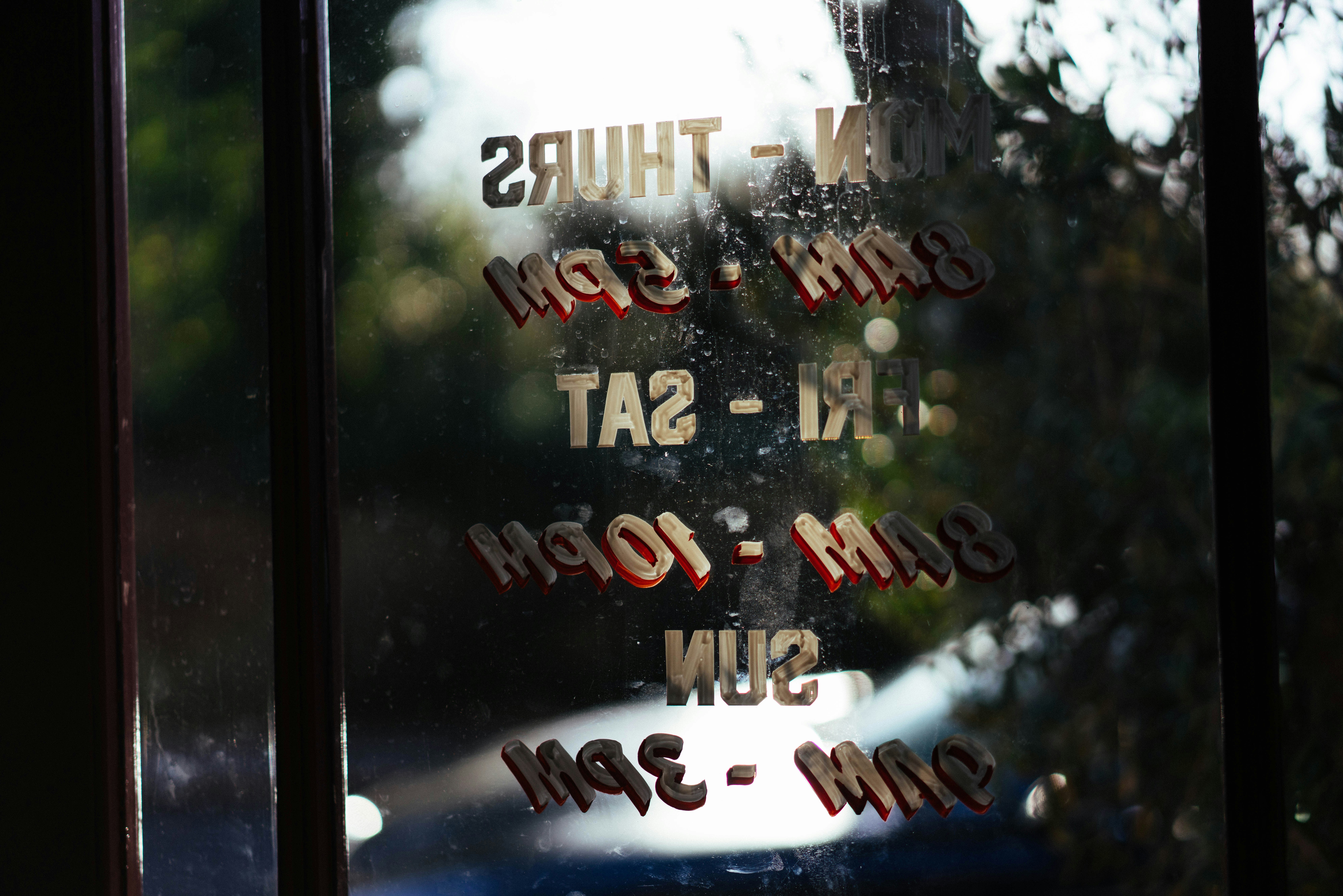 Store hours written on a glass door