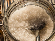 Close-up of coarse sugar crystals in a glass jar.