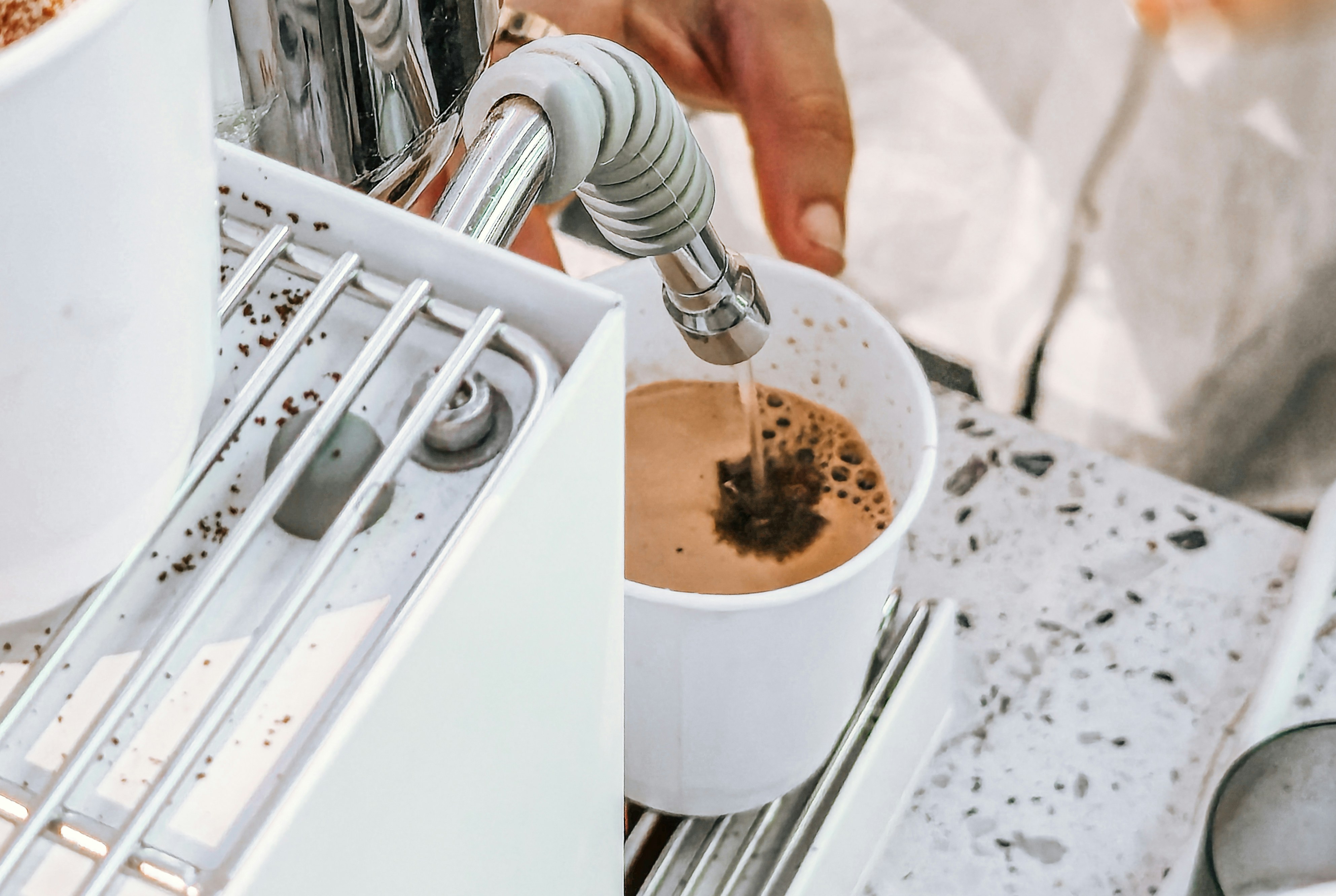 Barista pouring coffee into a white cup