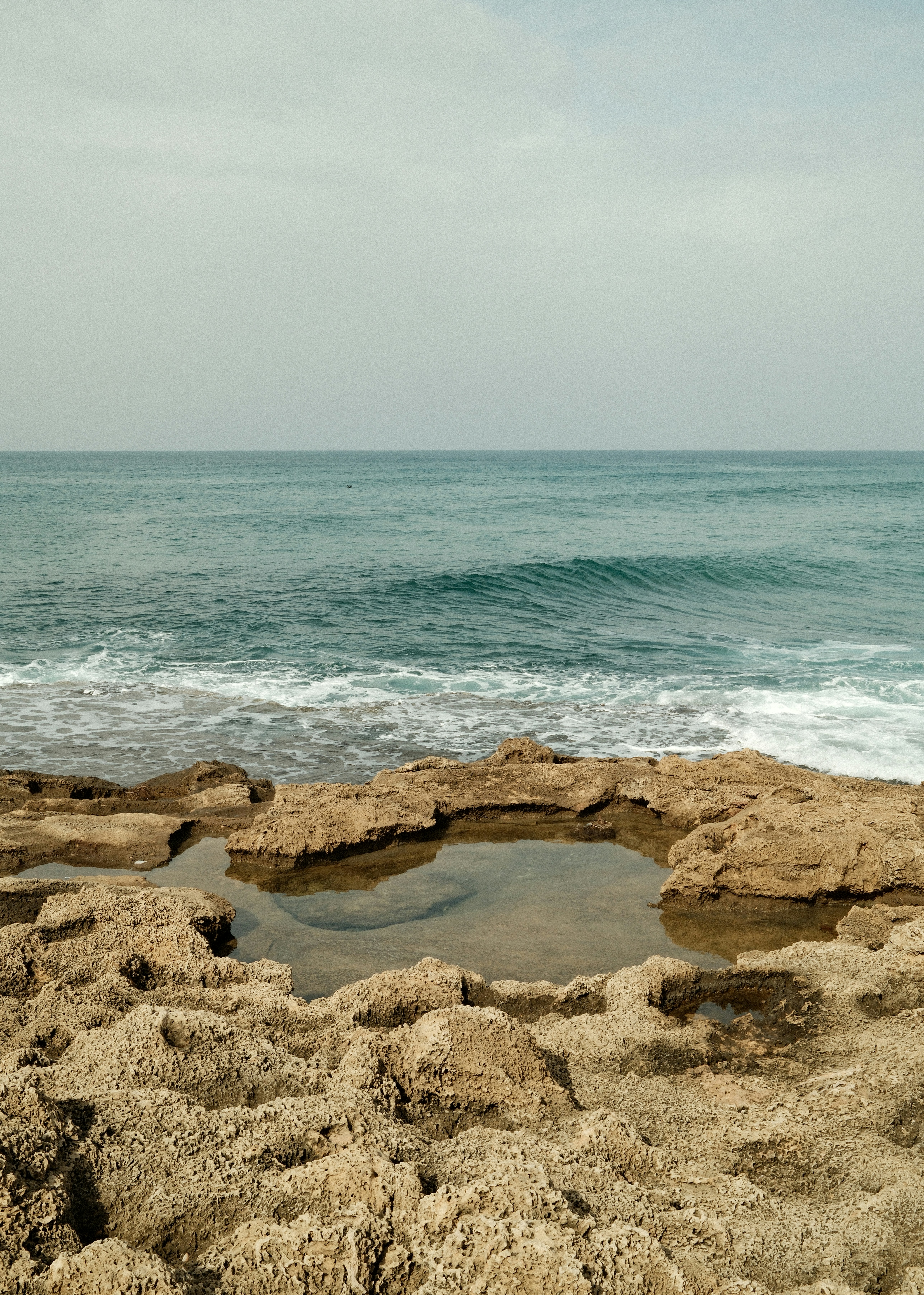 Ocean waves crash on rocky shore with tide pool