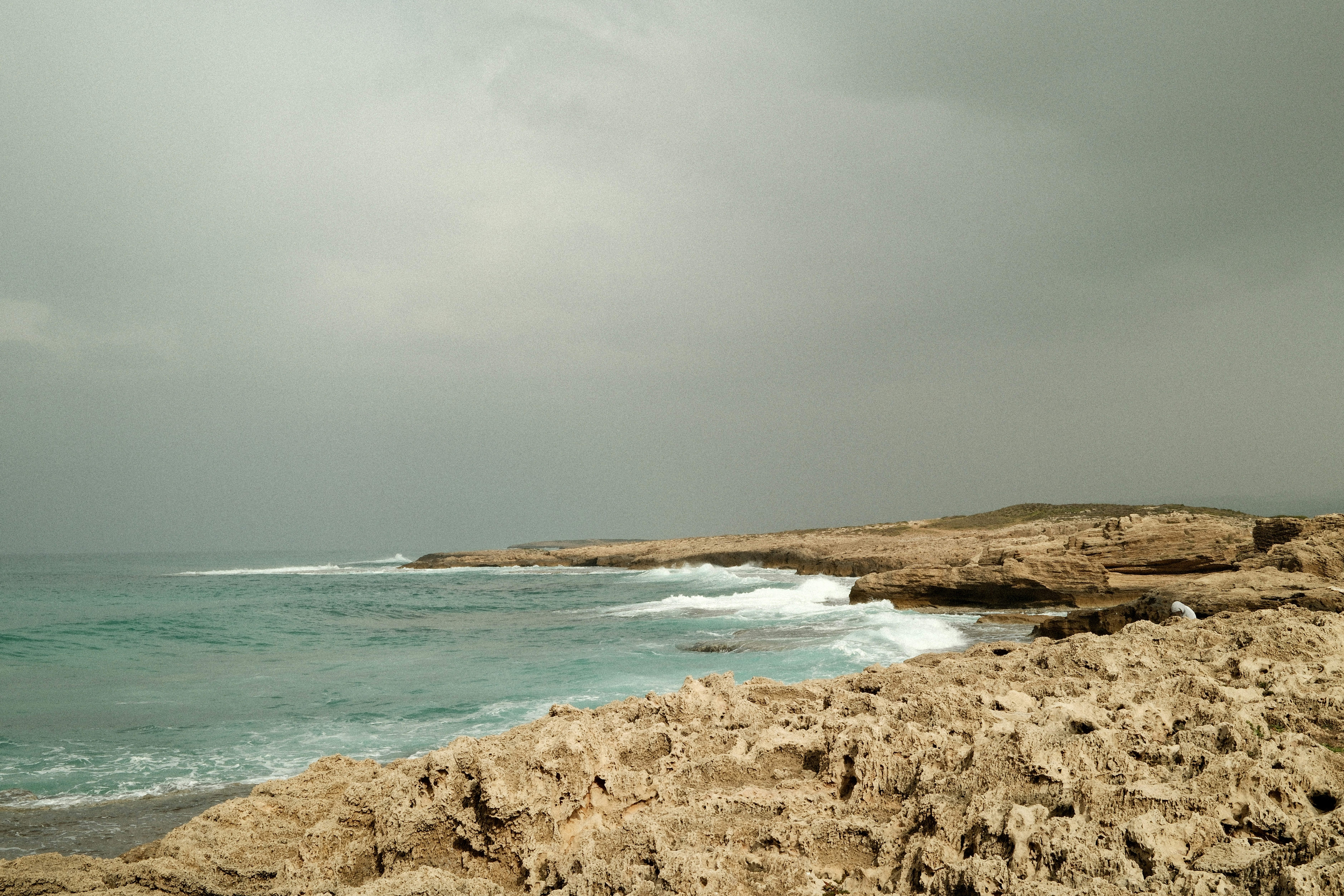 Rocky coastline with waves crashing under a cloudy sky