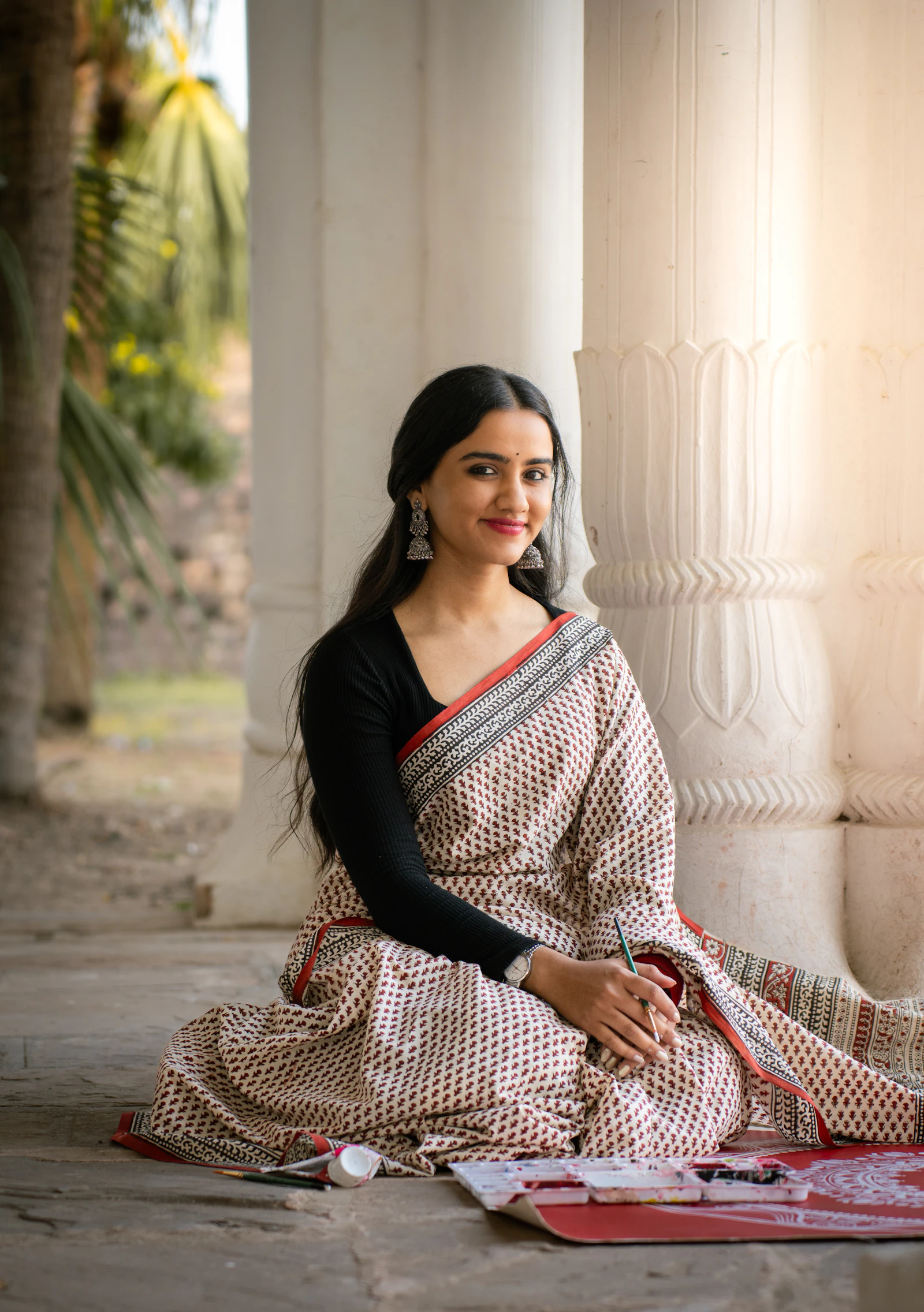 A woman in a pastel Chanderi saree by a temple pillar