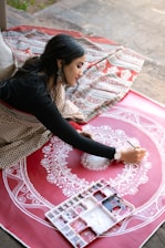 A woman painting a circular design on a red surface.