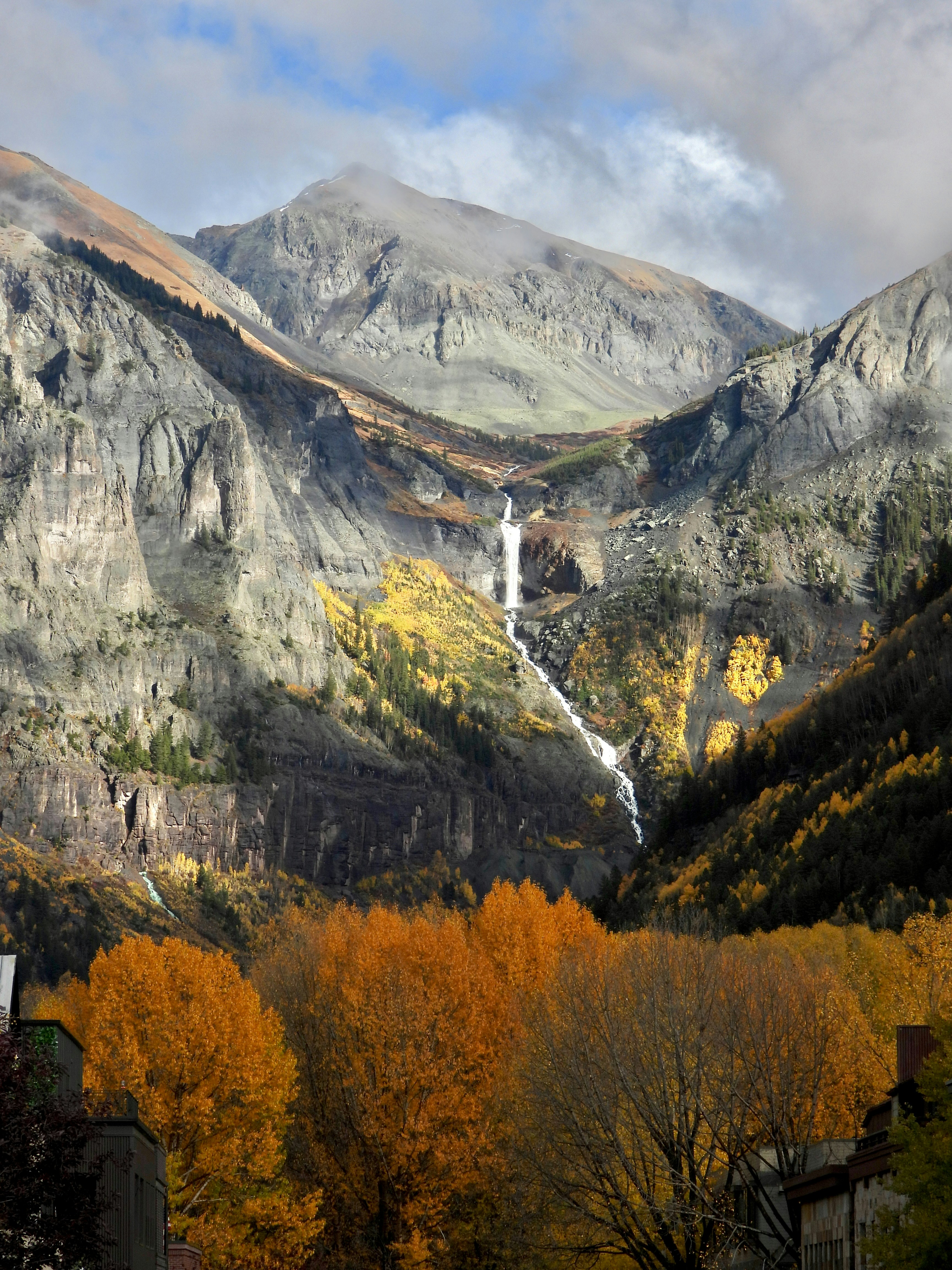 Waterfall cascading down a rocky mountain with autumn trees