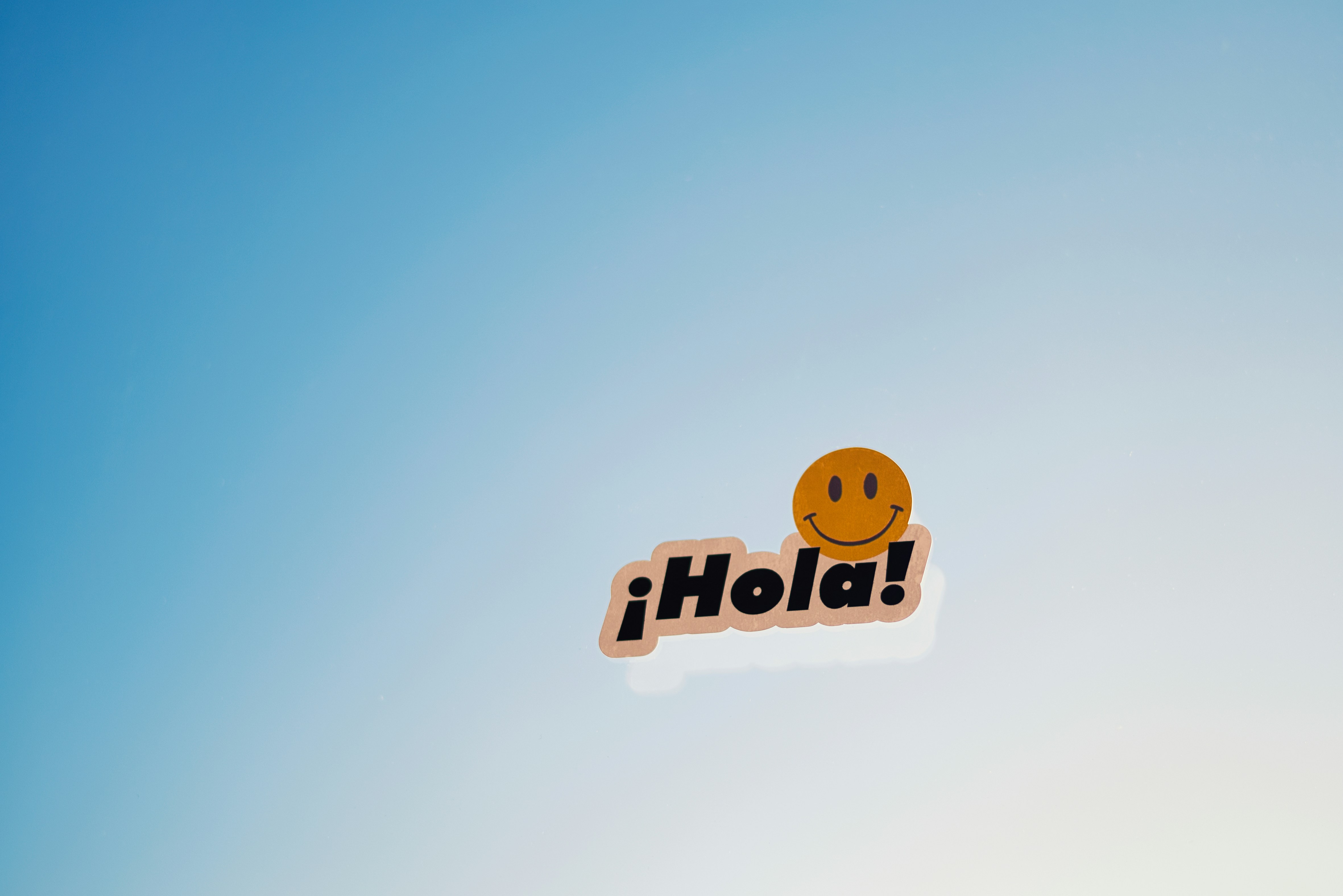 Una pegatina de cara sonriente con la palabra hola