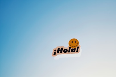 A smiley face sticker with the word hola