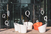Modern chairs outside a glass building with letter qs