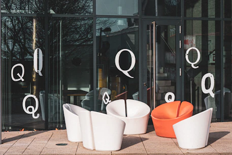Modern chairs outside a glass building with letter qs