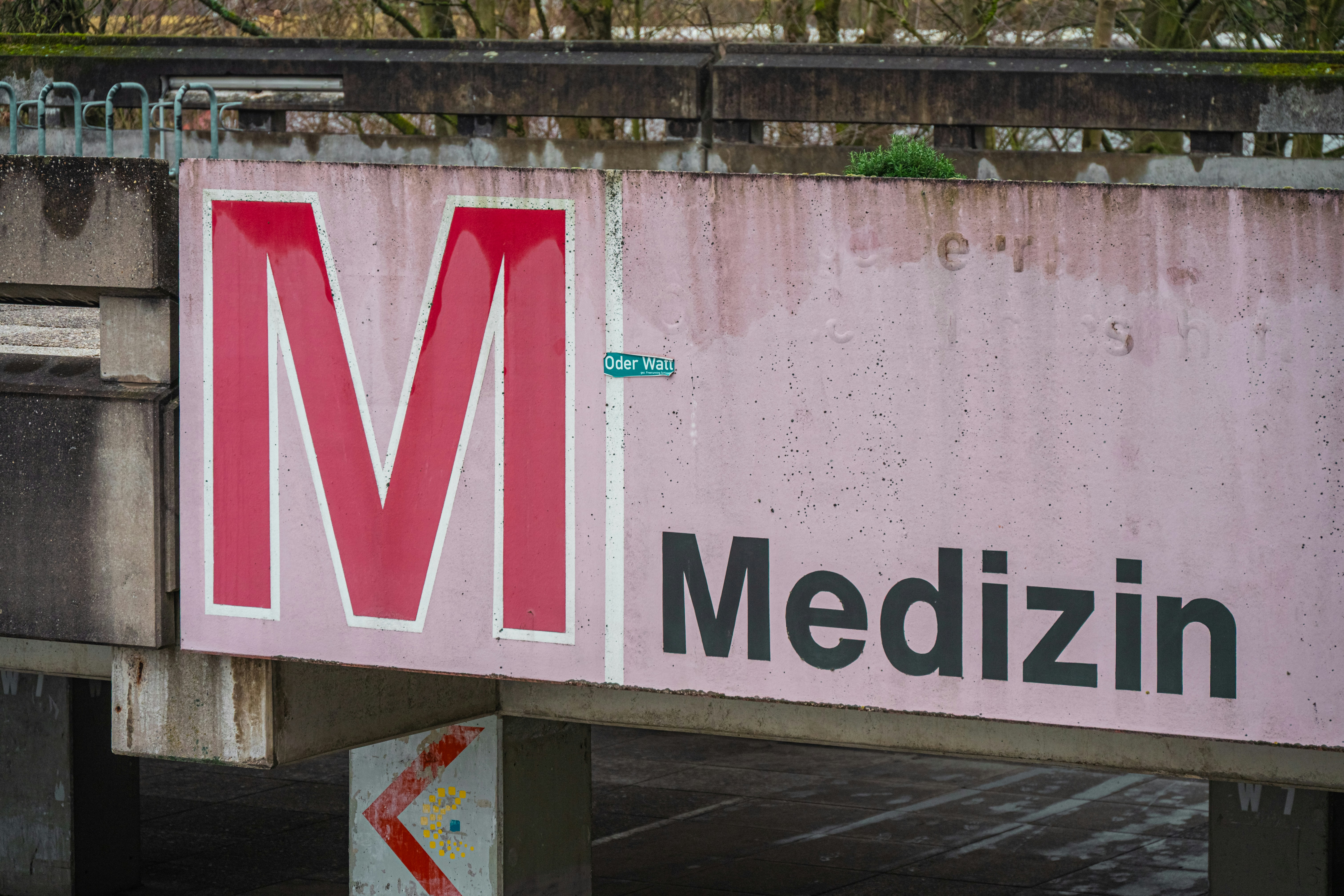 Large red m and "medizin" sign on concrete structure.