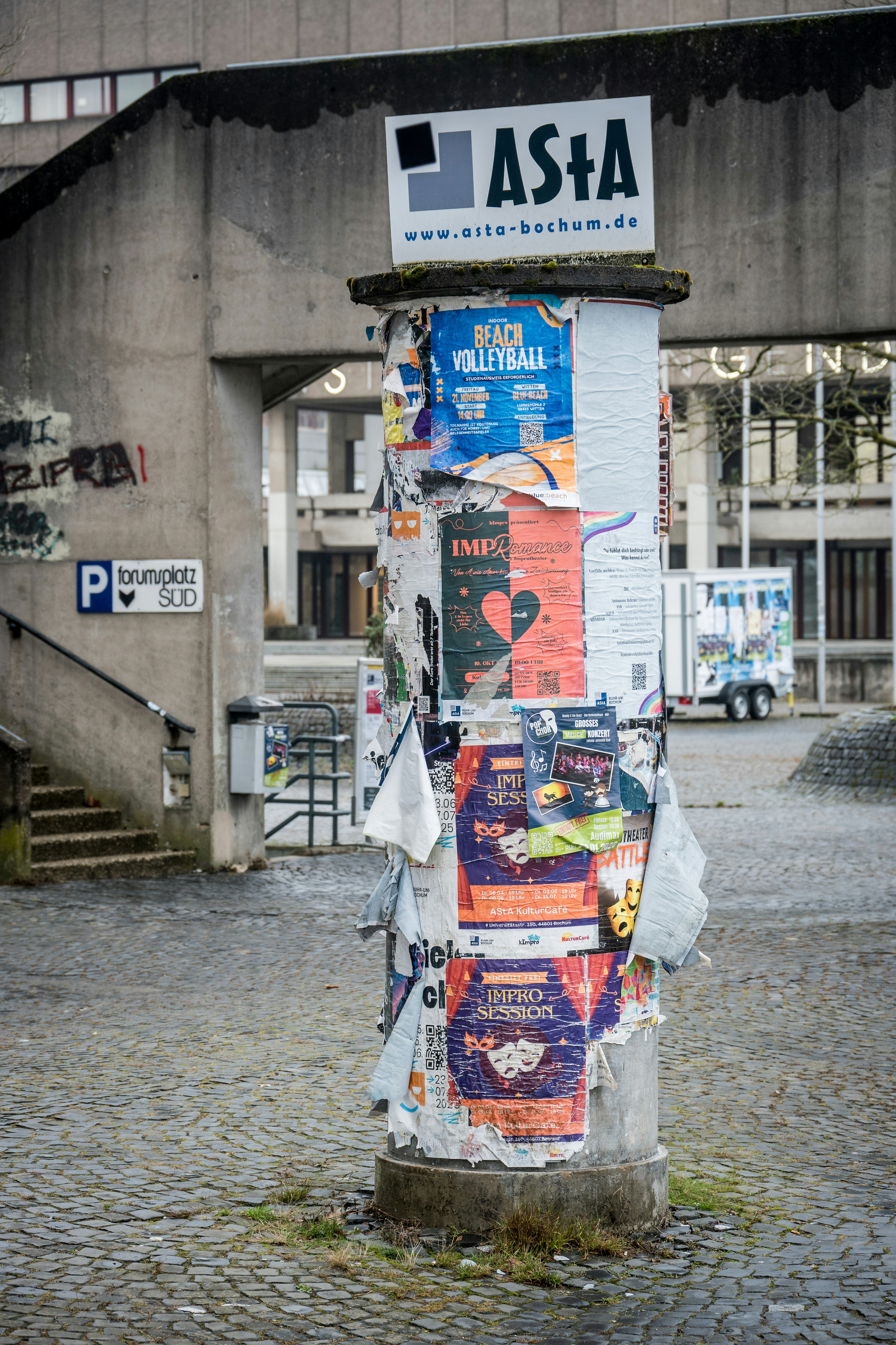 Une colonne usée couverte d’affiches déchirées.
