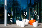 Modern chairs outside a glass building with letter q