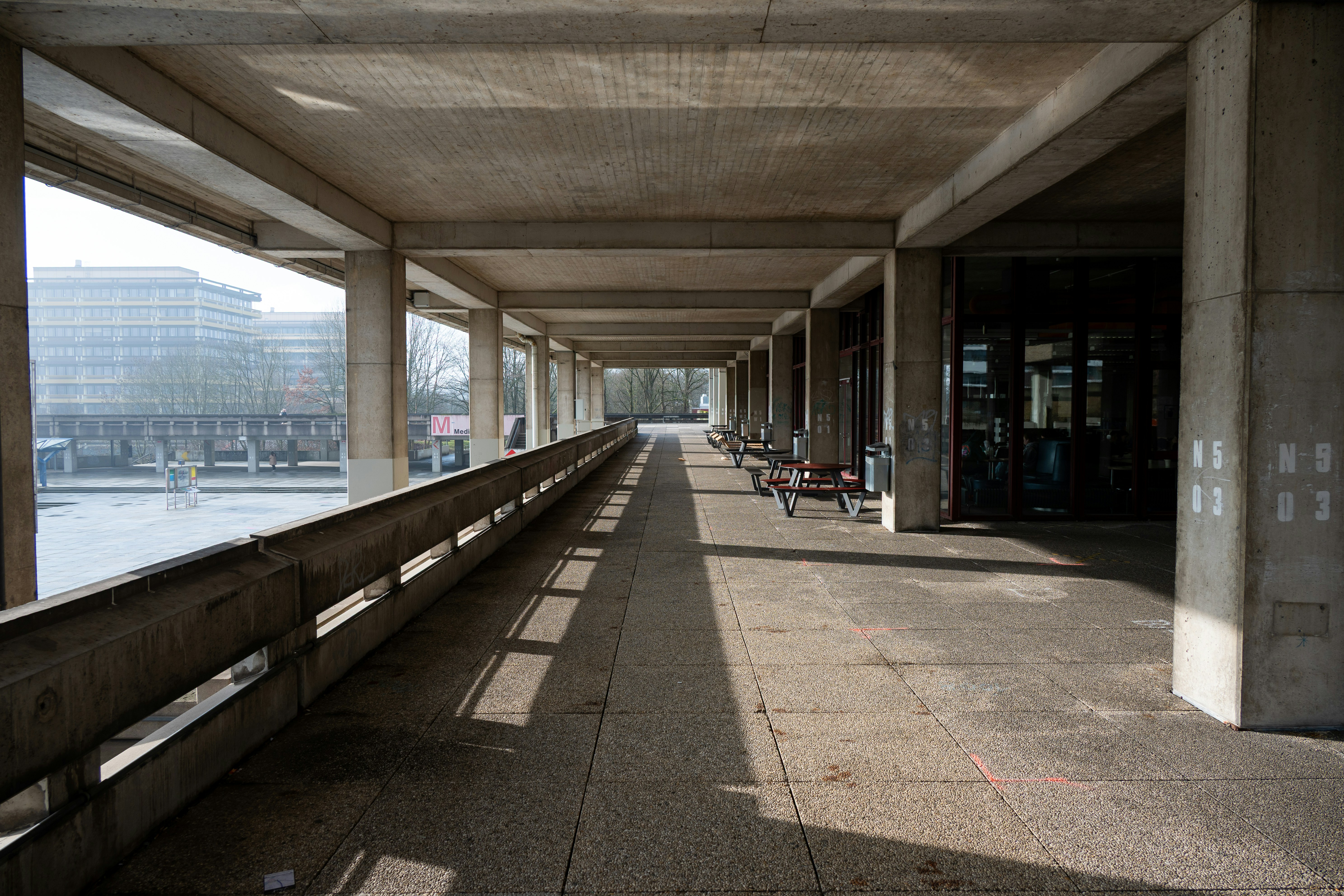 Concrete walkway with columns and benches outdoors.